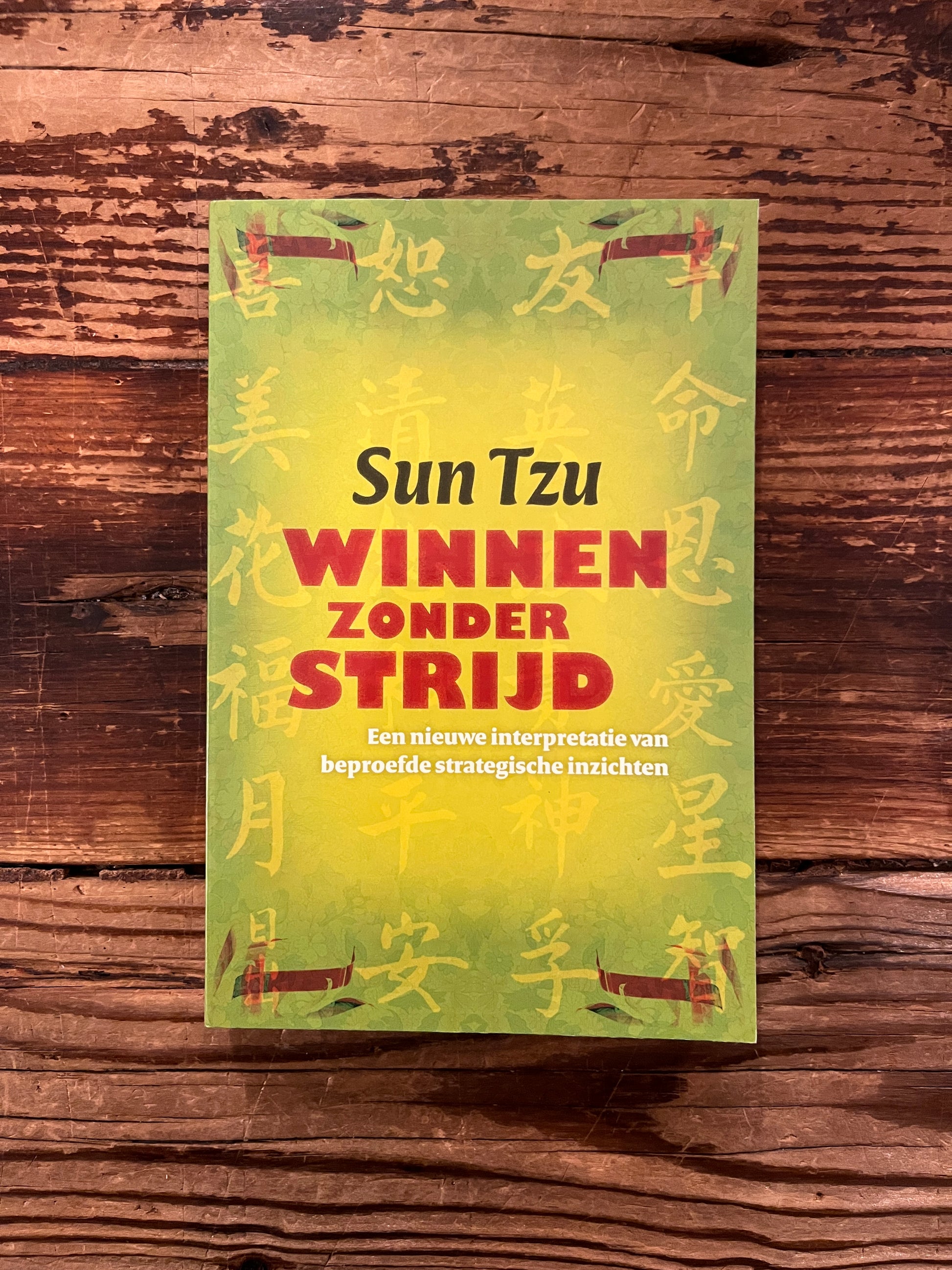 Boek met de titel 'Winnen zonder Strijd' door Sun Tzu op een houten 