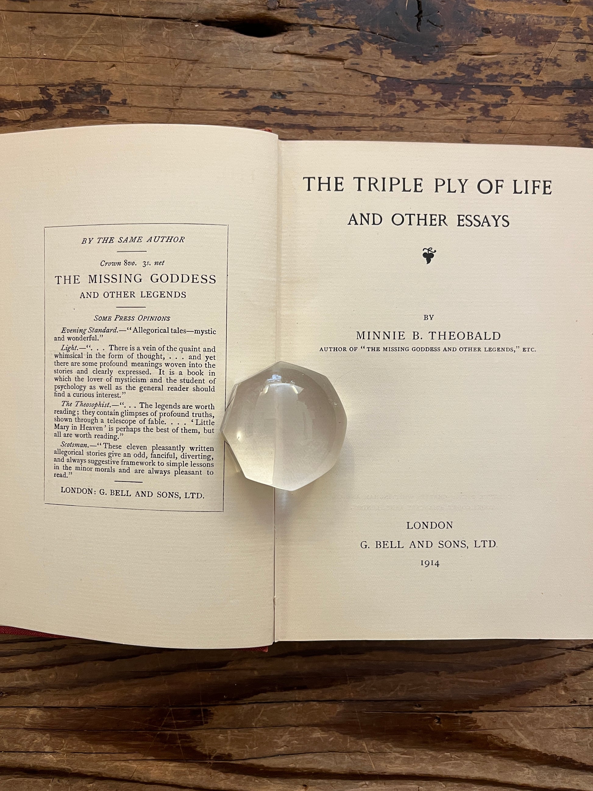 Open book titled 'The Triple Ply of Life' by Minnie E. Theobald on a wooden surface