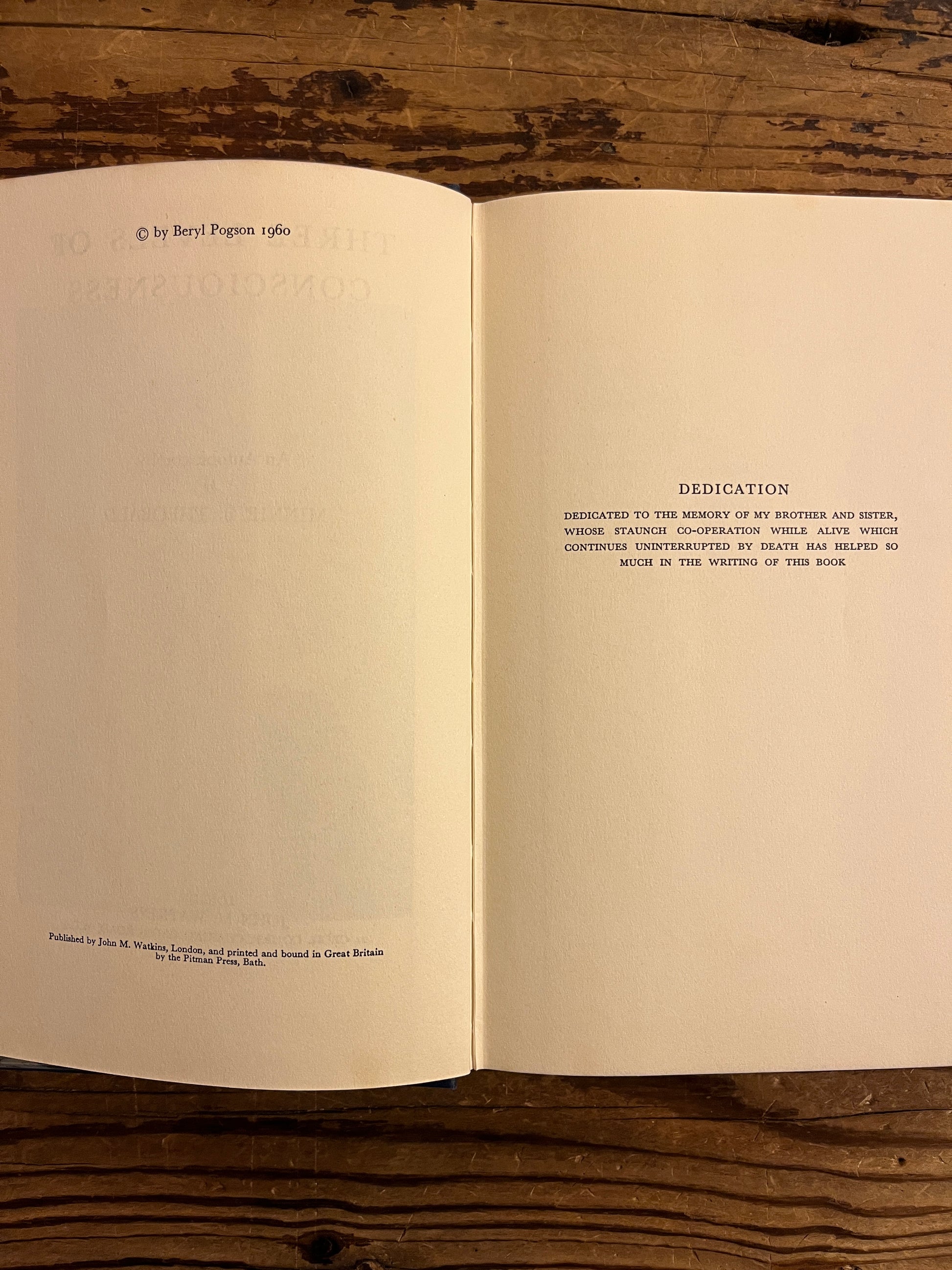 Open book 'three levels of consciousness' by Minnie B. Theobald on a wooden surface 