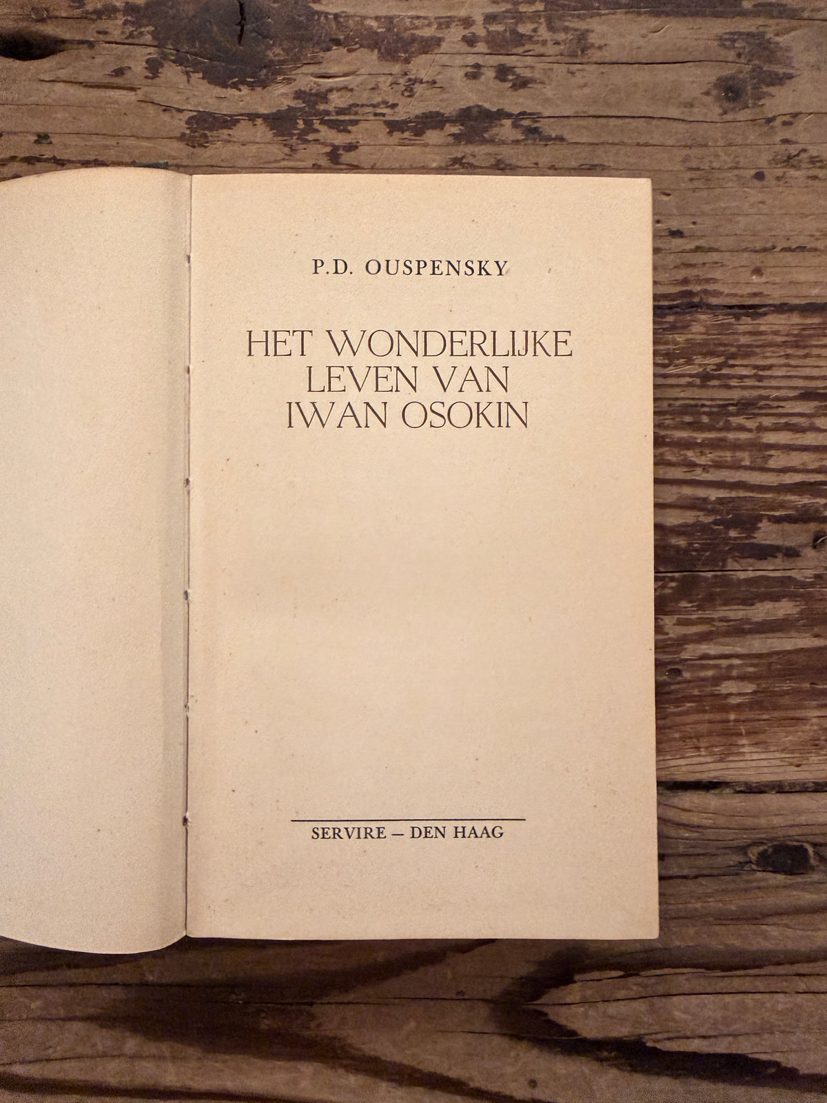 Eerste pagina van boek met de titel 'Iwan Osokin' door P.D. Ouspensky op een houten achtergrond 