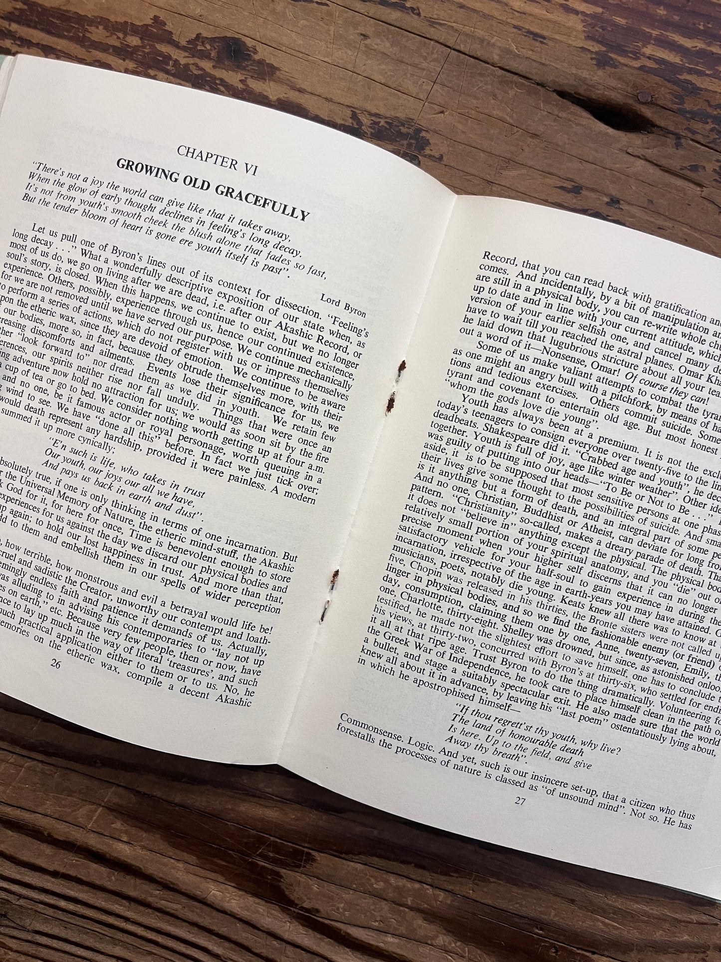 Open booklet with the title 'Prisoners of time' by Mollie Moncrieff, showing the two inner staples being rusted, on a wooden surface 