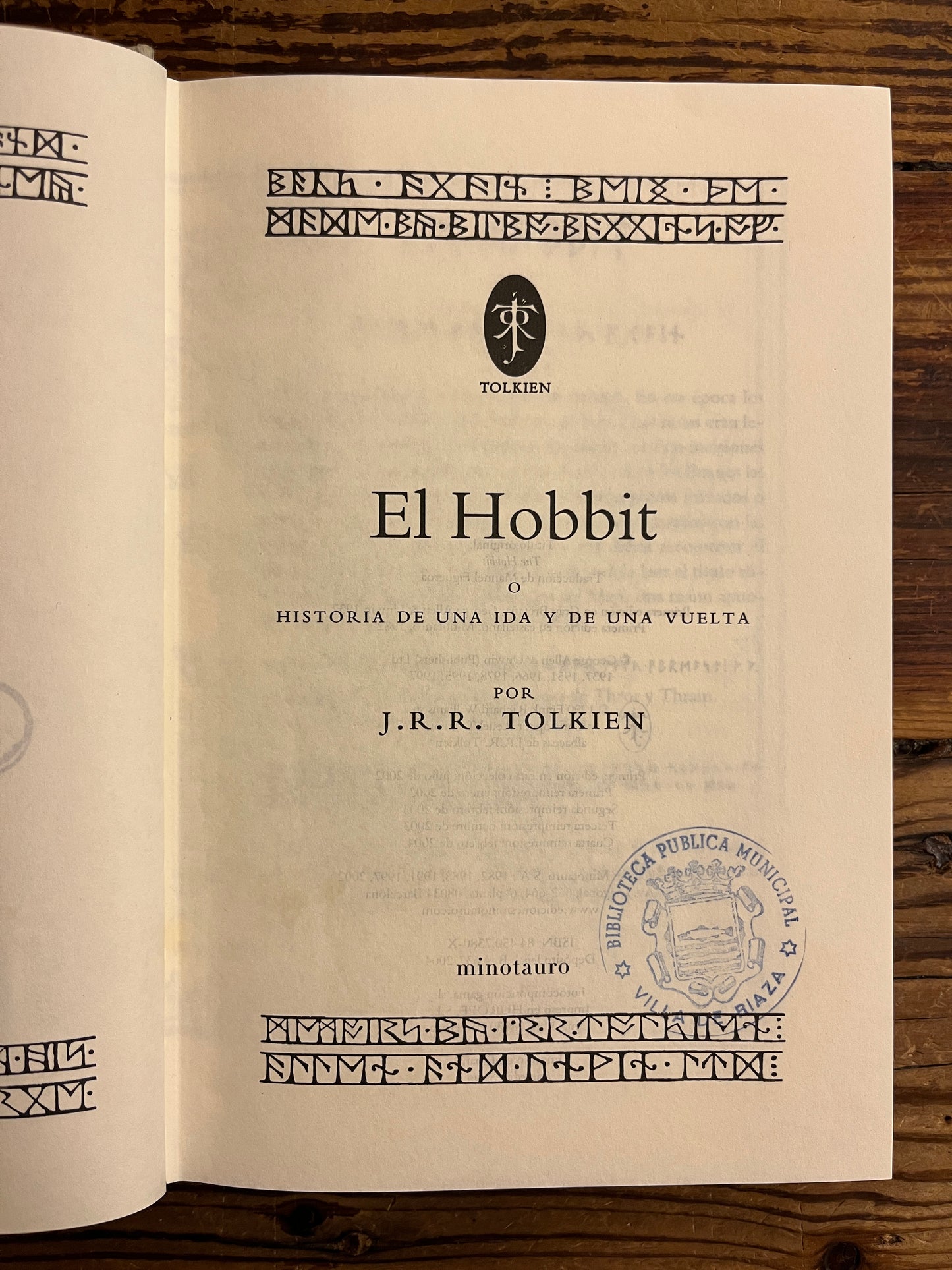 Open book with 'El Hobbit' by J.R.R. Tolkien on a wooden surface