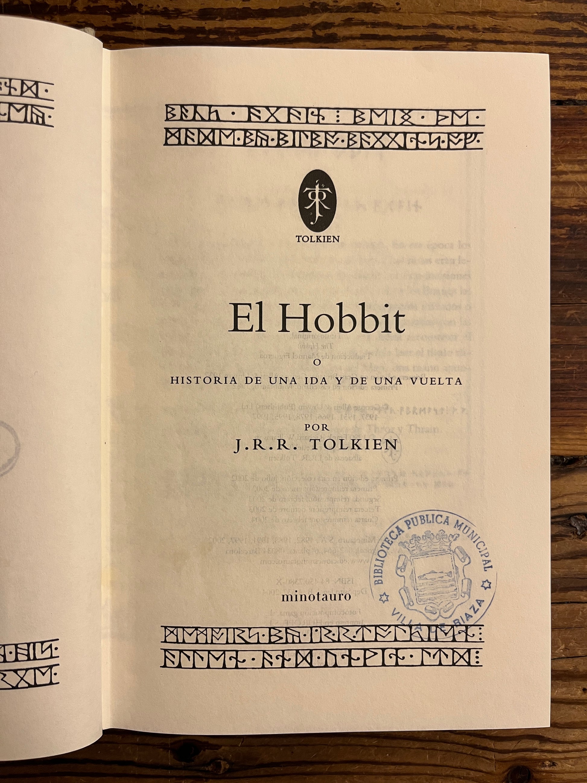 Open book with 'El Hobbit' by J.R.R. Tolkien on a wooden surface