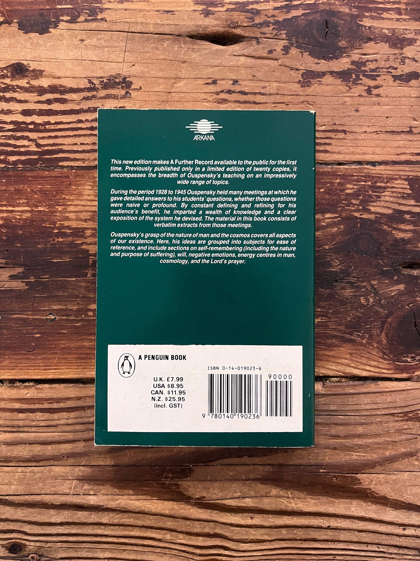 Back cover of a book with the title 'A further record extracts from meetings 1928-1945' by P. D. Ouspensky on a wooden surface