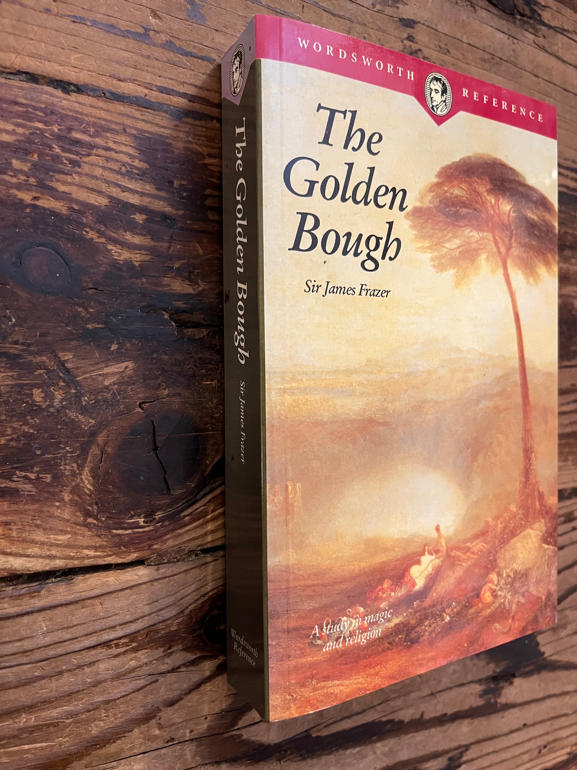 book titled 'The Golden Bough' by James G. Frazer on a wooden surface