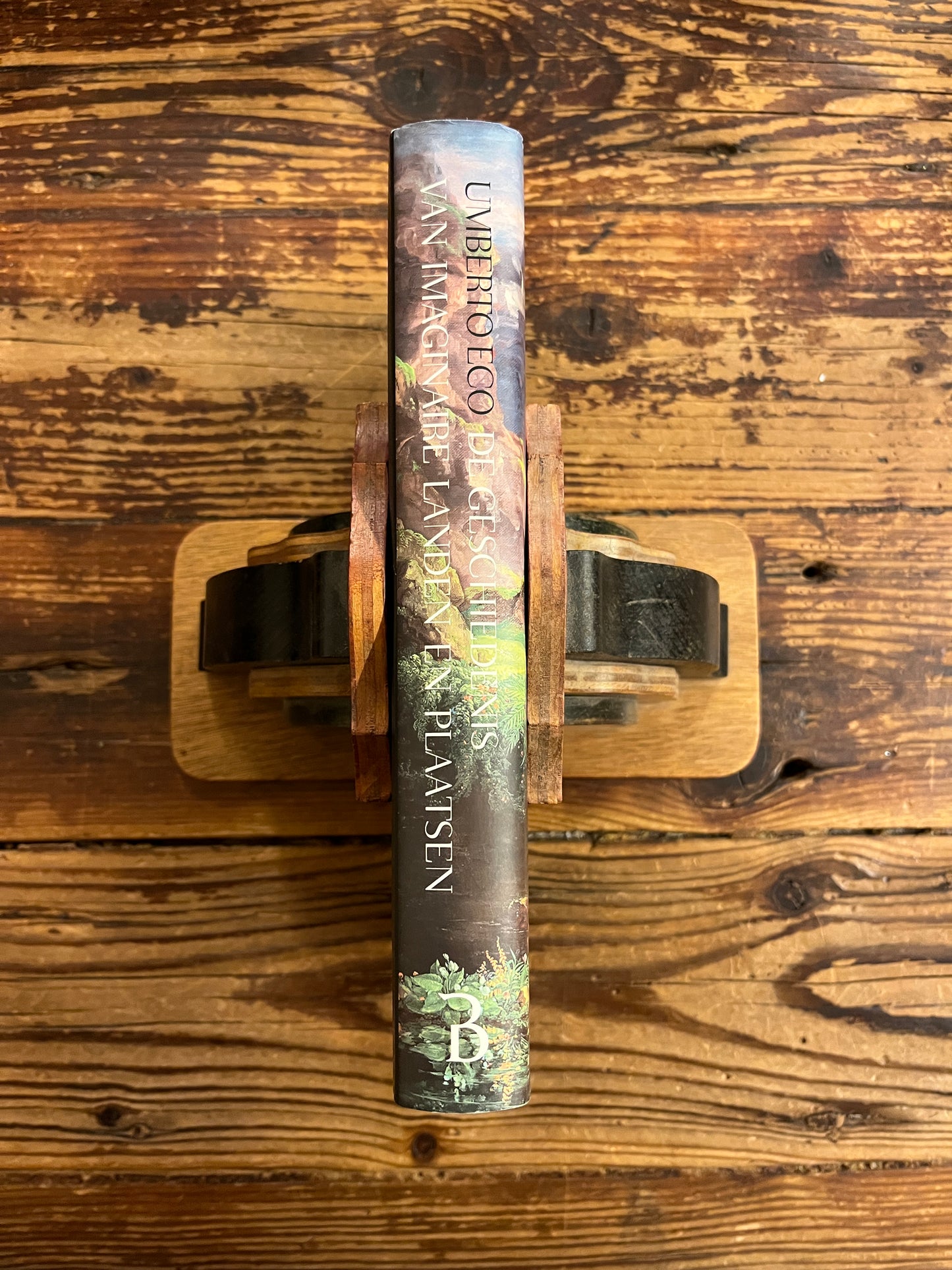 Rug van boek met de titel 'De Geschiedenis Van Imaginaire Landen En Plaatsen' door Umberto Eco op een houten achtergrond 