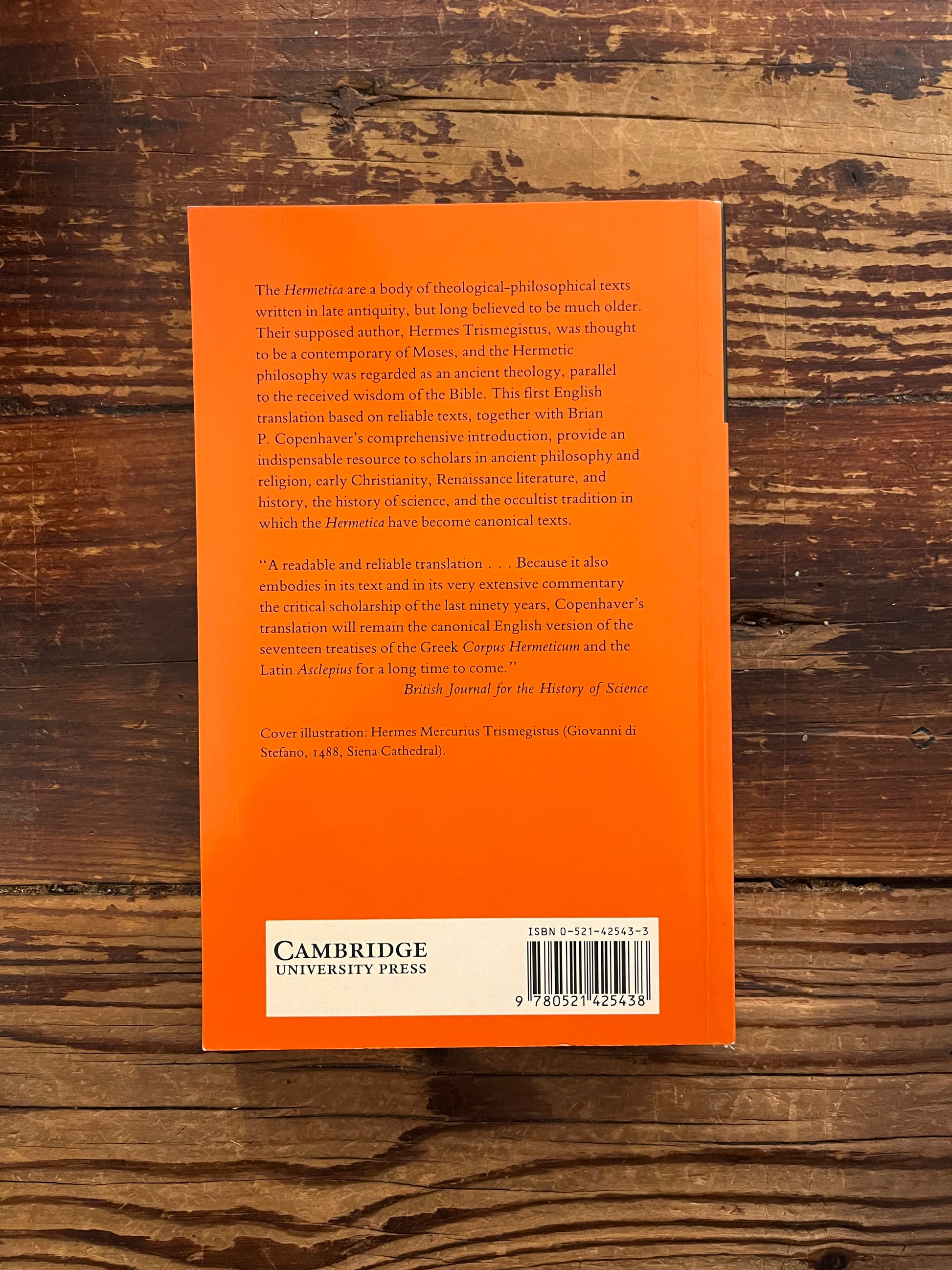 Back cover of book with the title 'Hermetica' door Brian P. Copenhaver on a wooden surface