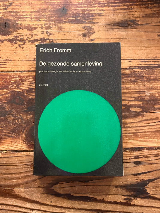 Boek met de titel 'De gezonde samenleving' door Erich Fromm op een houten achtergrond 