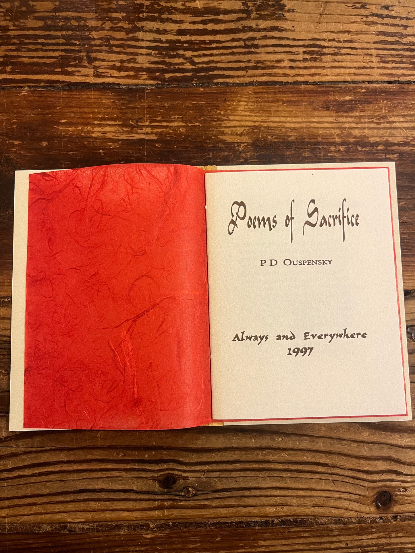 open book titled 'Poems of Sacrifice' by P.D. Ouspensky on a wooden surface
