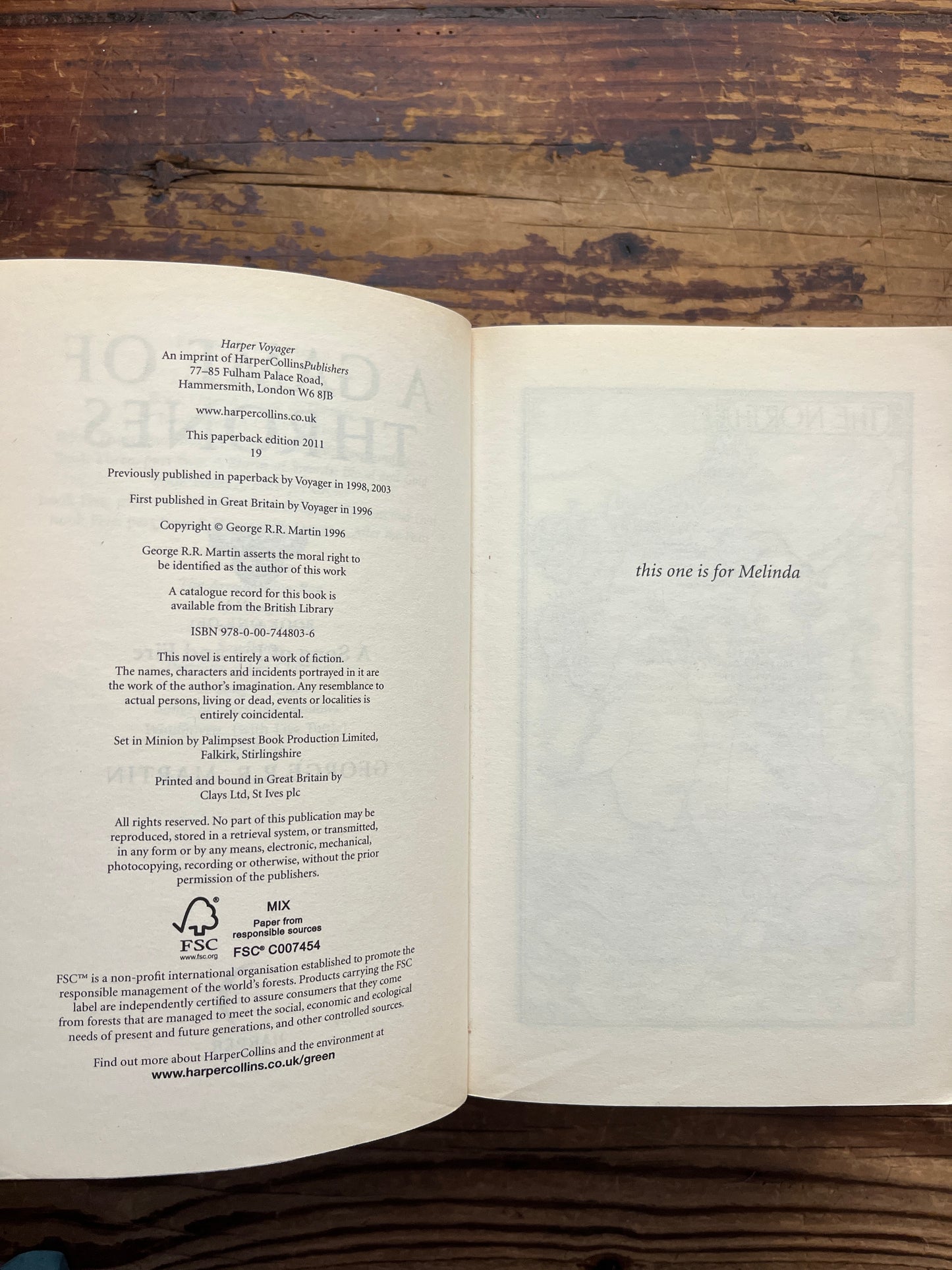 Open book titled 'A Game of Thrones' by George R.R. Martin on a wooden surface