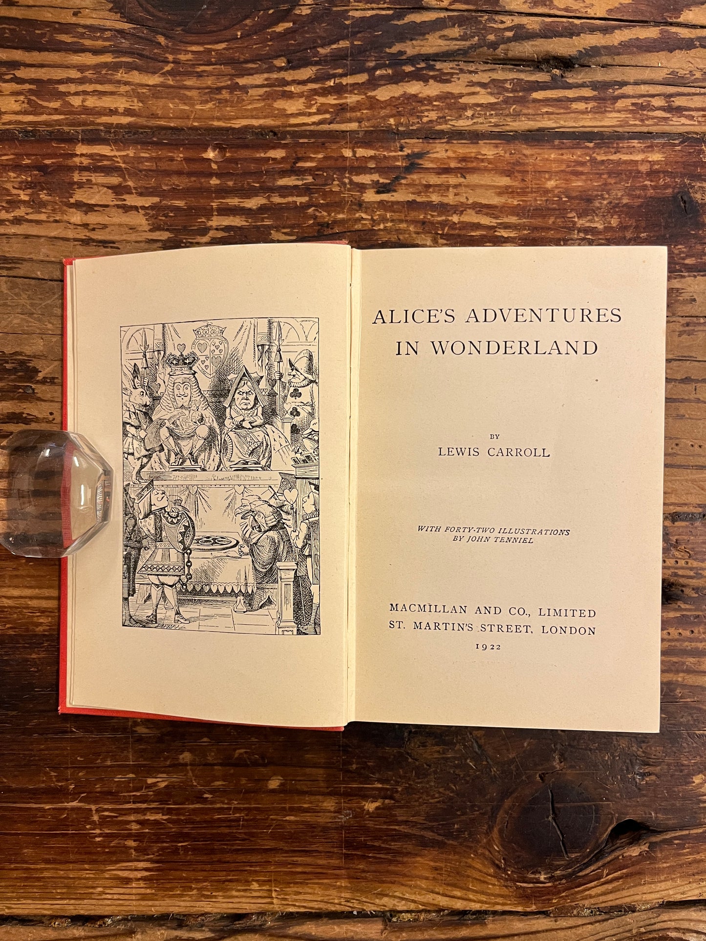 Open book showing the title page, this book is a 1922 macmillan & co miniature edition of 'Alice's adventures in wonderland' by Lewis Carroll on a wooden surface