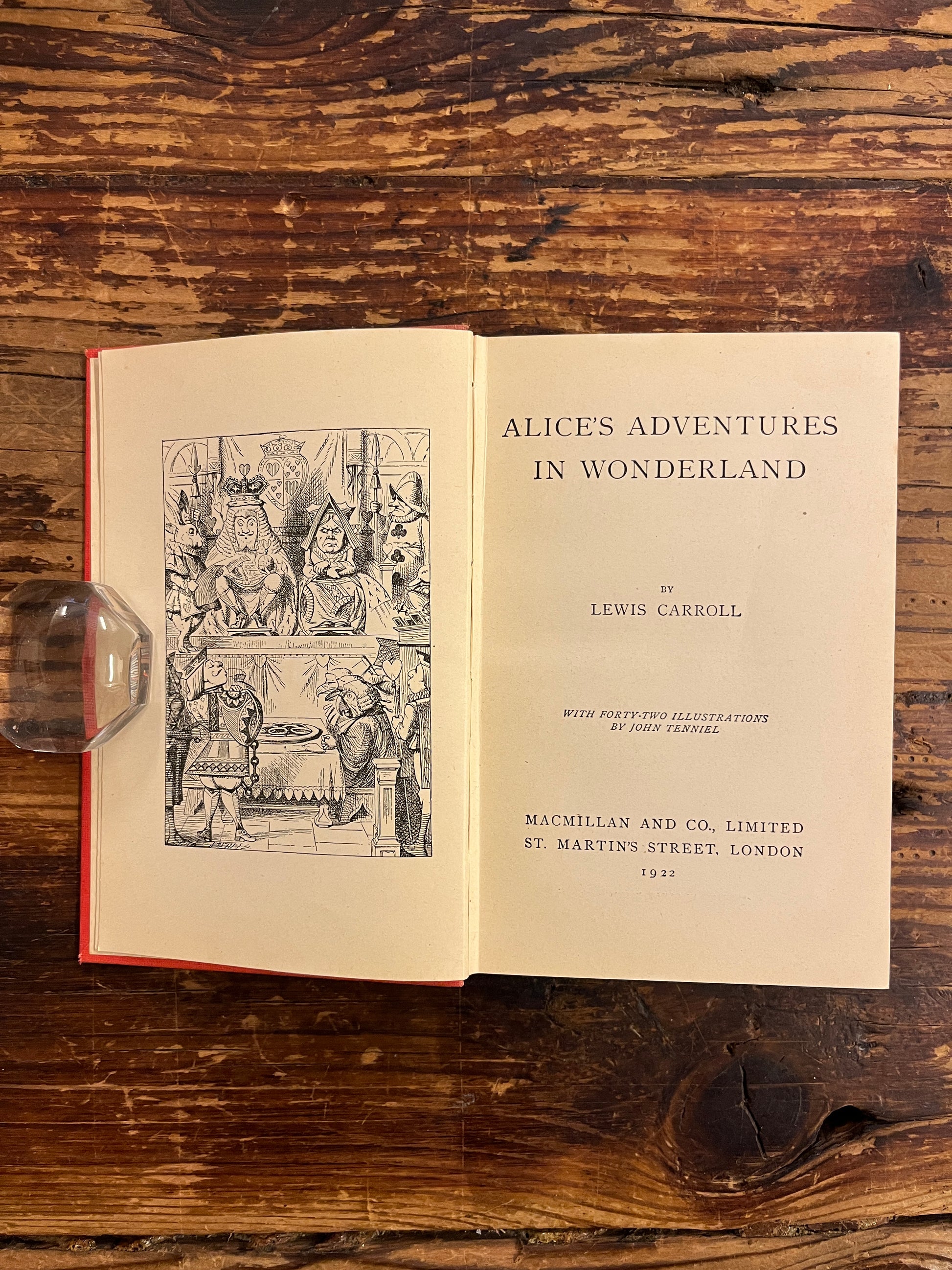 Open book showing the title page, this book is a 1922 macmillan & co miniature edition of 'Alice's adventures in wonderland' by Lewis Carroll on a wooden surface