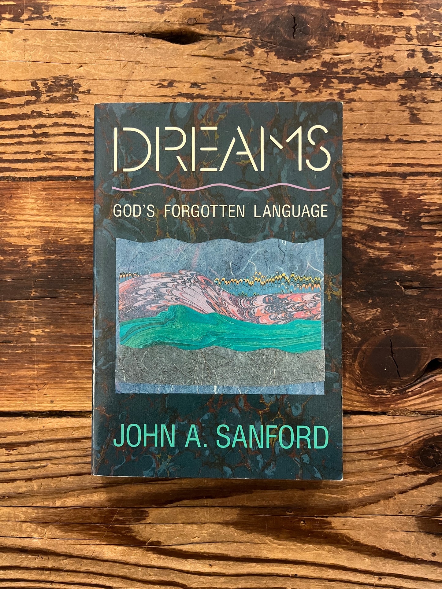 Book titled 'Dreams: God's Forgotten Language' by John A. Sanford on a wooden surface