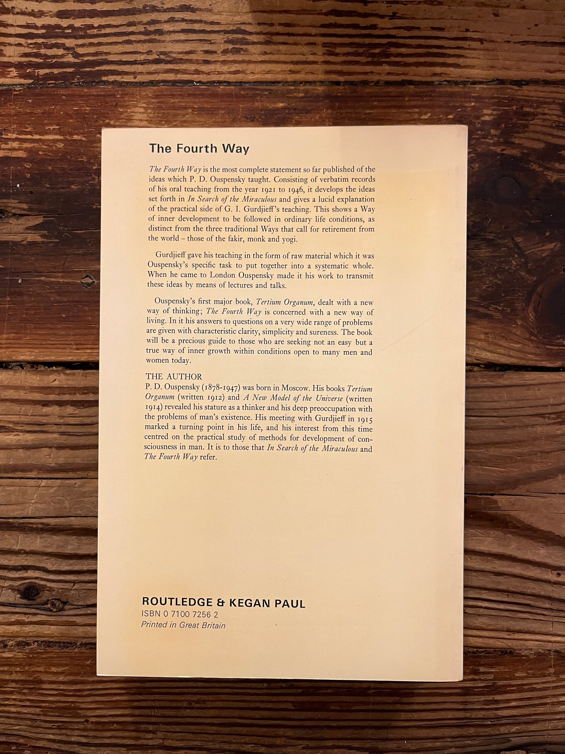 Back cover of a book with the title 'the fourth way' by P.D. Ouspensky on a wooden surface 