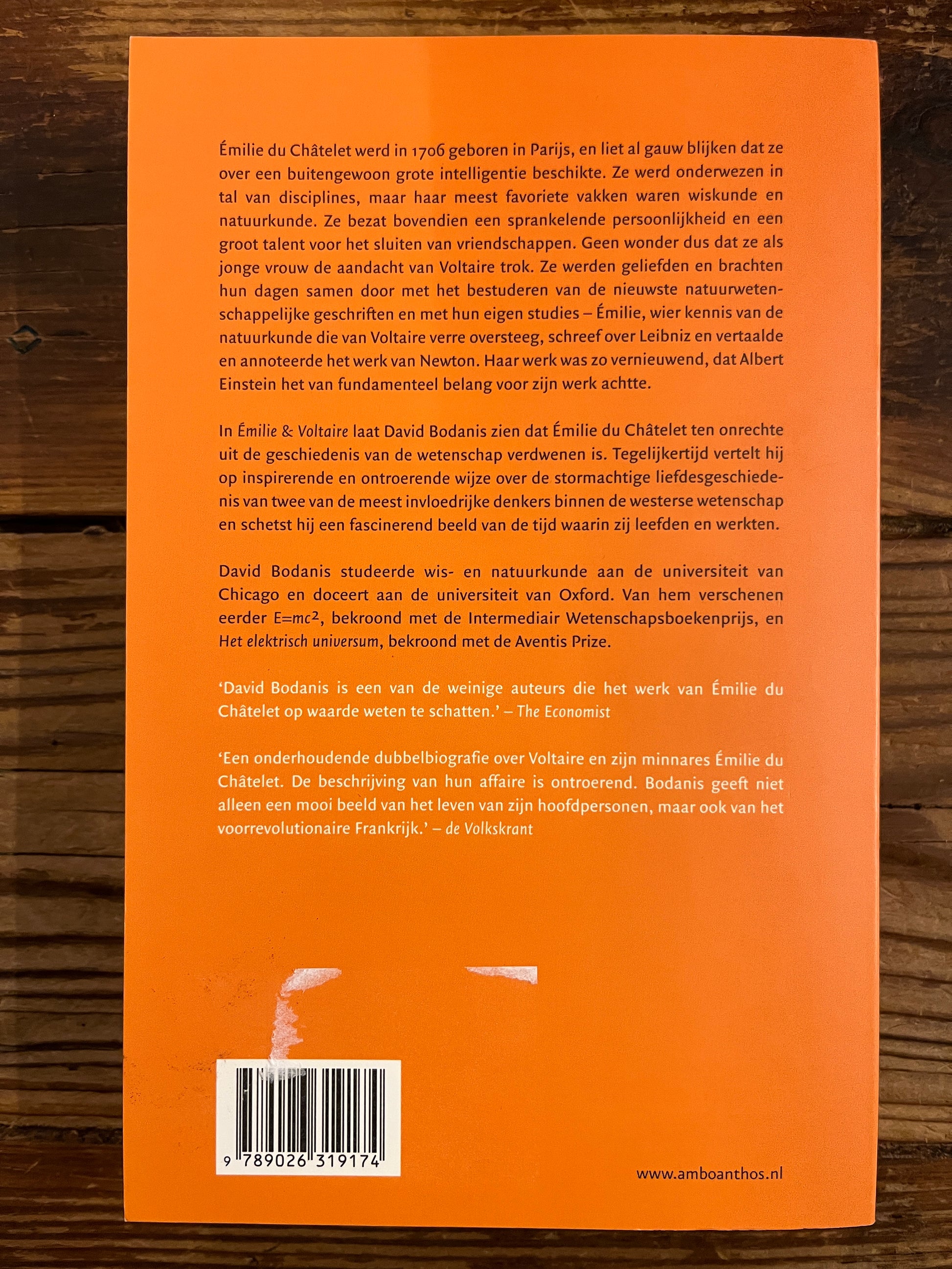 Achterkant van  boek met de titel 'Emilie & Voltaire' door David Bodanis op een houten achtergrond 