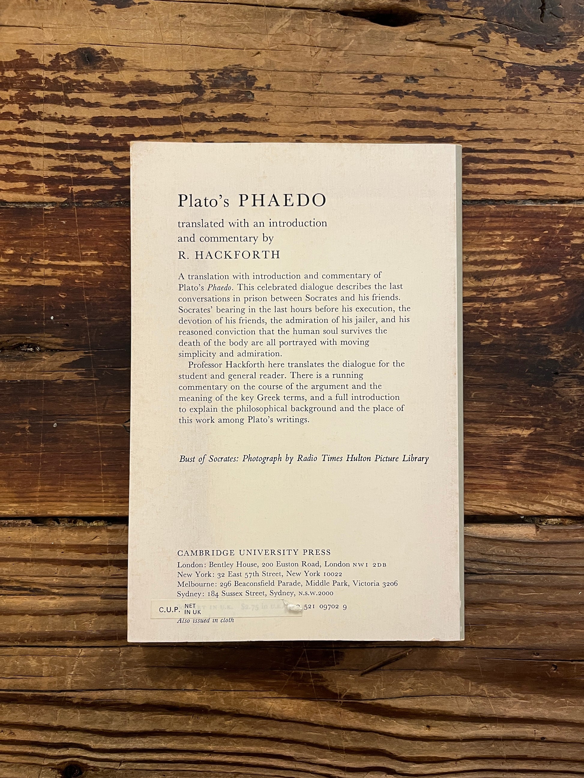 Back cover of book titled 'Plato's Phaedo' translated with an introduction and commentary by R. Hackforth on a wooden surface