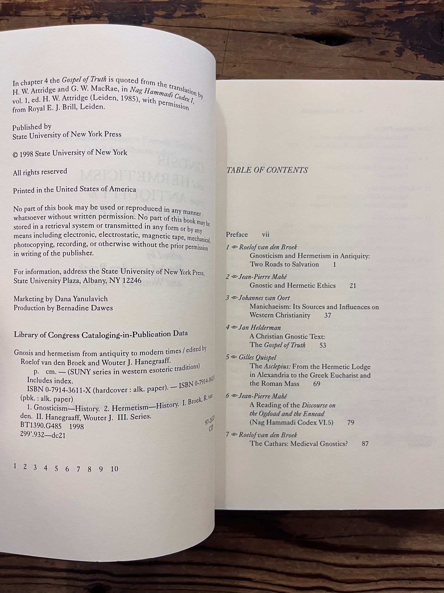Open book titled 'Gnosis and Hermeticism: From Antiquity to Modern Times' edited by Roelof van den Broek and Wouter J. Hanegraaff op een houten achtergrond 