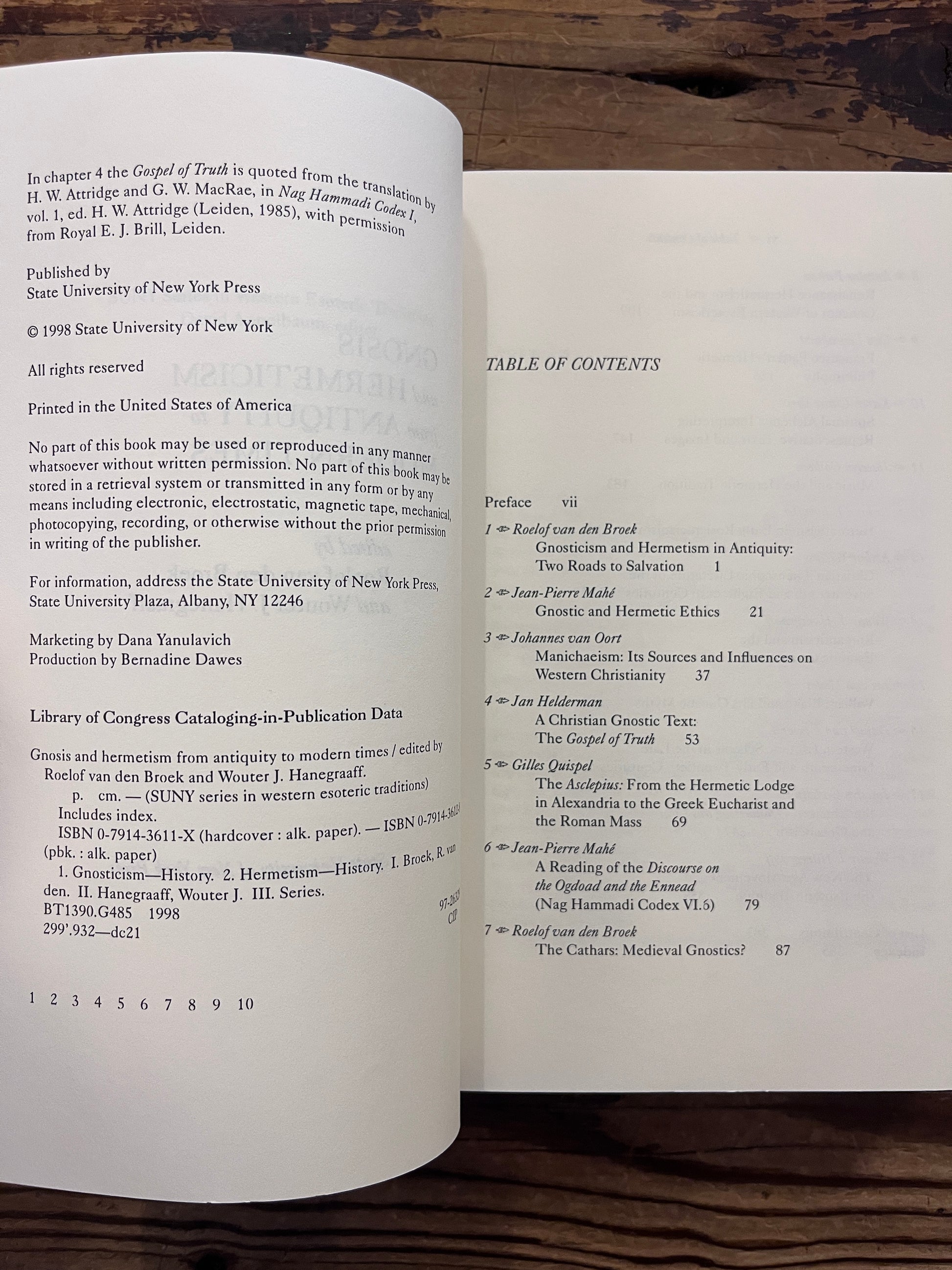 Open book titled 'Gnosis and Hermeticism: From Antiquity to Modern Times' edited by Roelof van den Broek and Wouter J. Hanegraaff op een houten achtergrond 