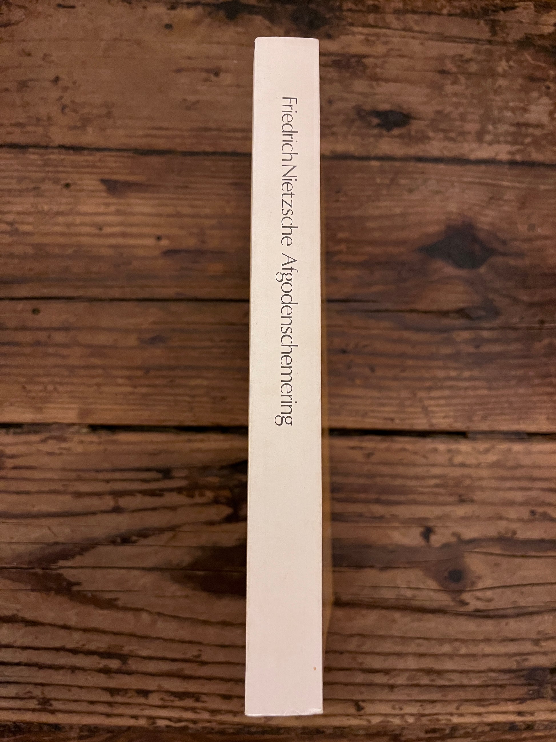 foto van de rug van het boek "Afgodenschermering" op een houten achetgrond