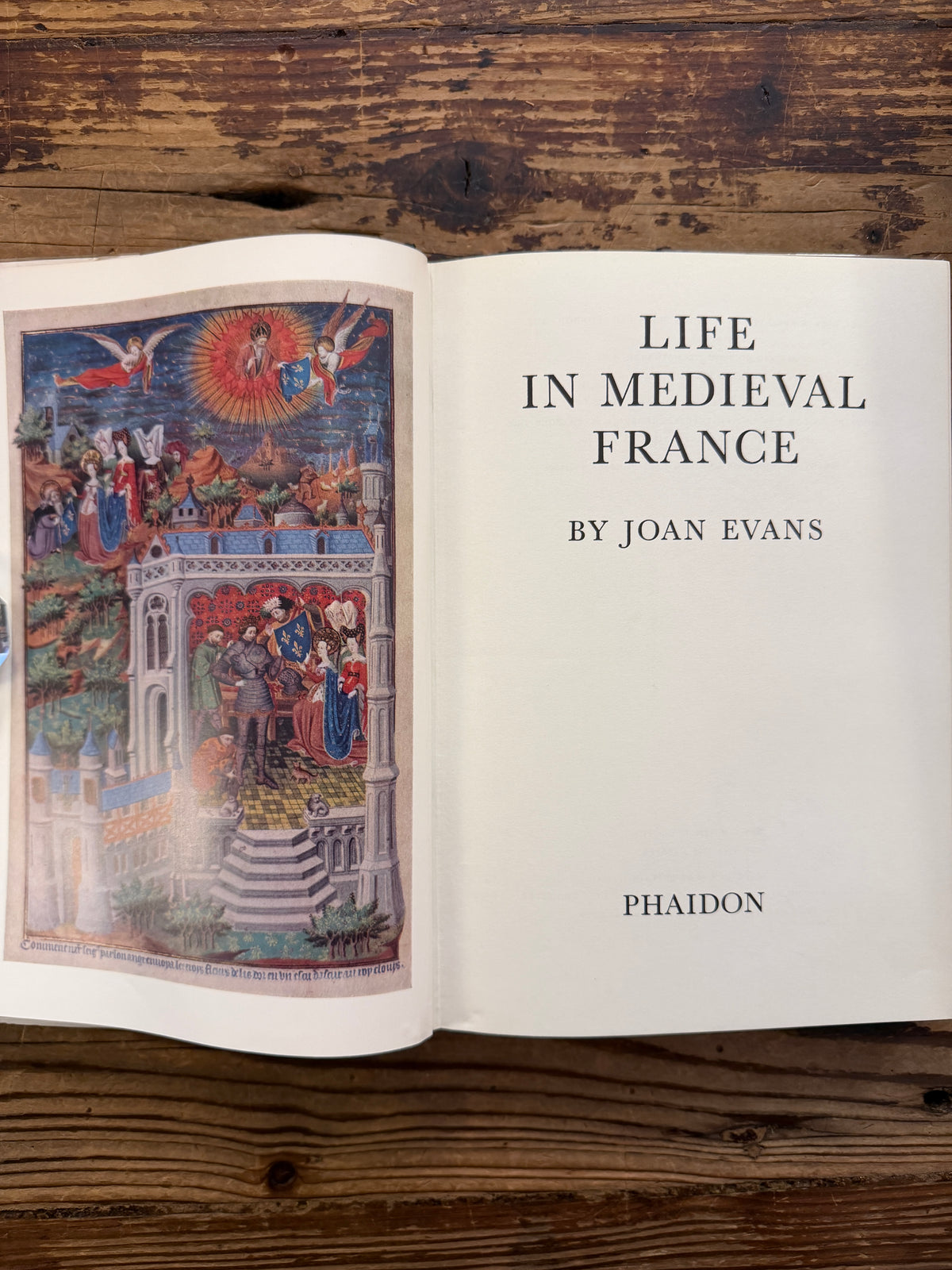 Open book titled 'Life in Medieval France' by Joan Evans, on a wooden surface
