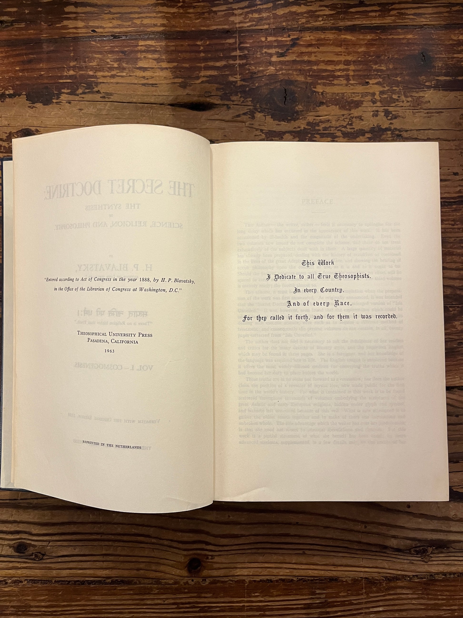 Open book titled 'The Secret Doctrine' by H.P. Blavatsky on a wooden surface.