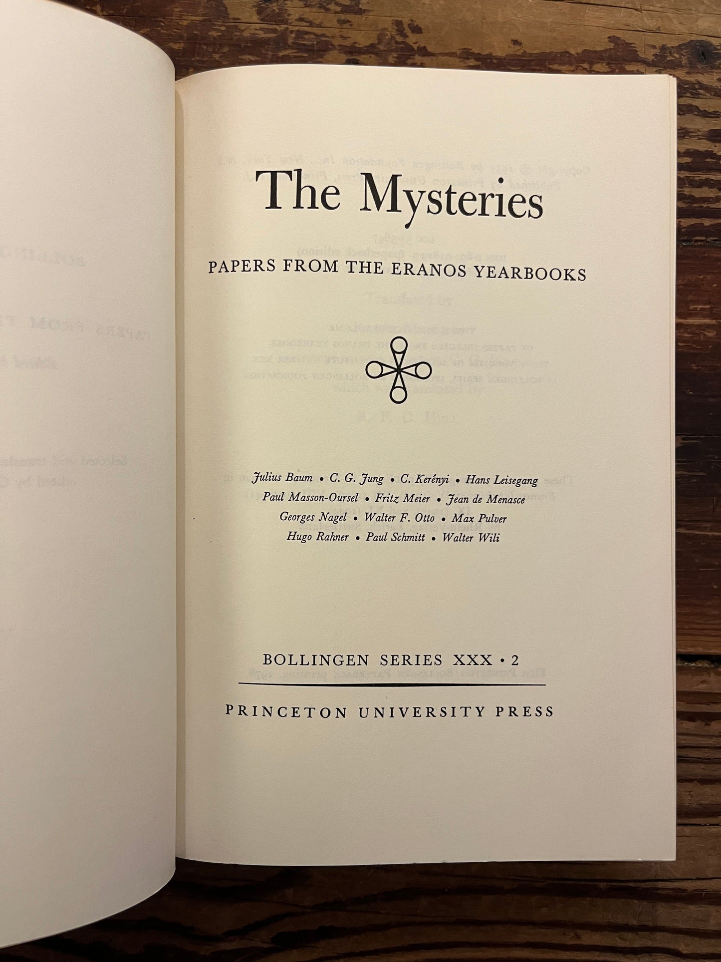 Open book titled 'The Mysteries, papers from the Eranos Yearbooks' on a wooden surface