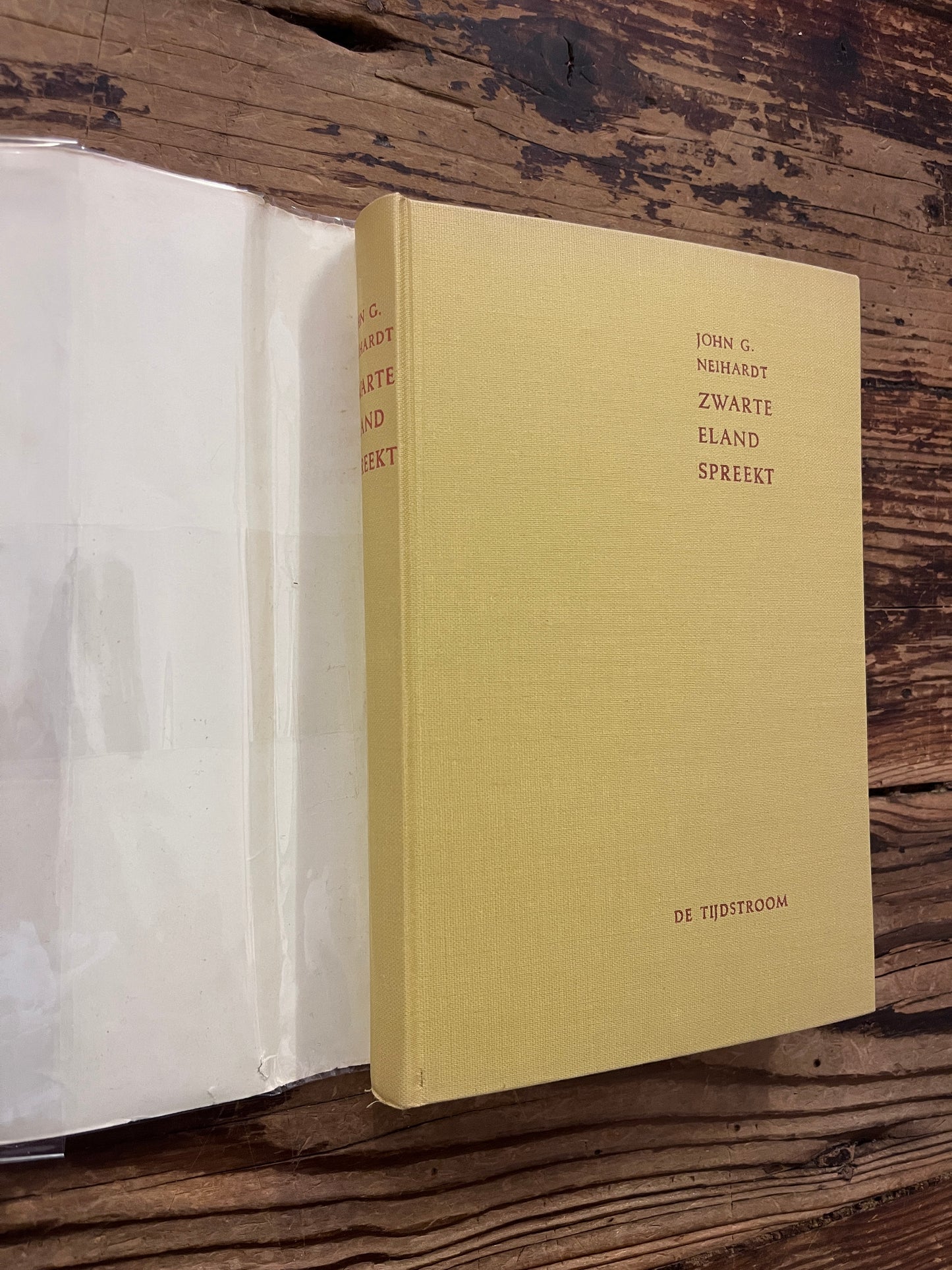 Voorkant en rug van hardcover boek onder de stof omslag met de titel 'Zwarte eland spreekt, Een Sioux-medicijnman verteld zijn leven' door John G. Neihardt op een houten achtergrond 