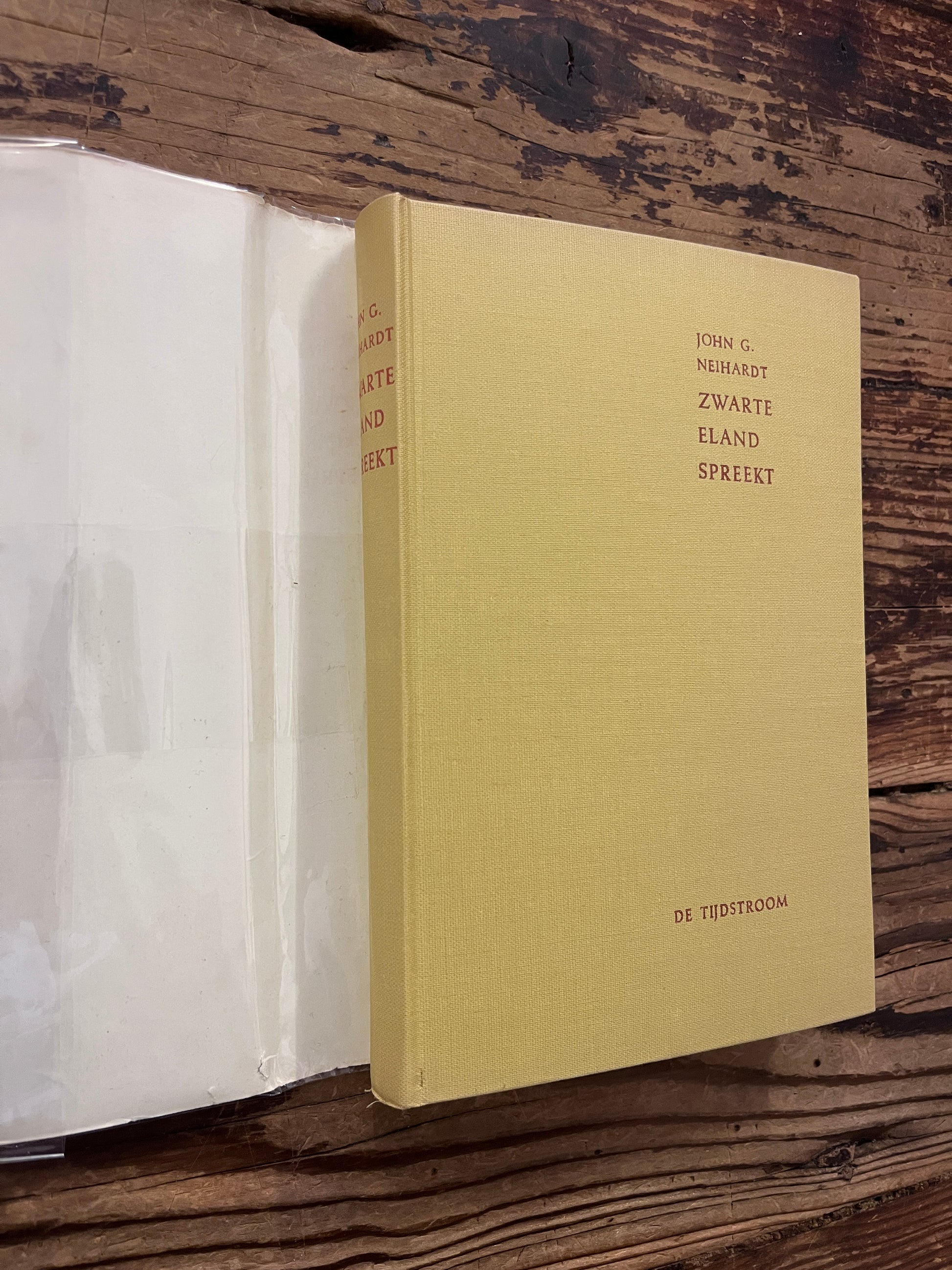 Voorkant en rug van hardcover boek onder de stof omslag met de titel 'Zwarte eland spreekt, Een Sioux-medicijnman verteld zijn leven' door John G. Neihardt op een houten achtergrond 