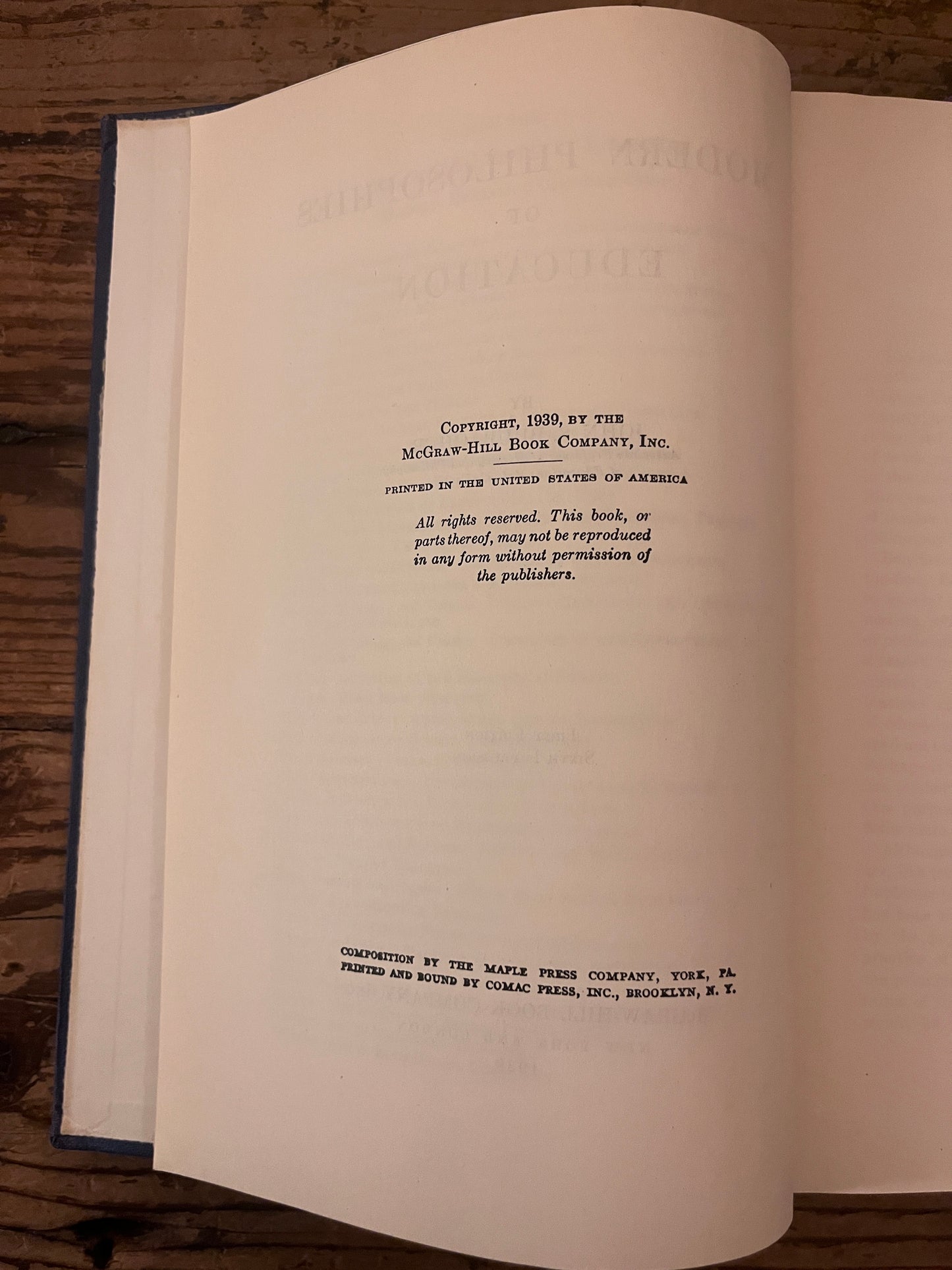 photo of the half title page of the book "modern philosophies of educatio" on a wooden background