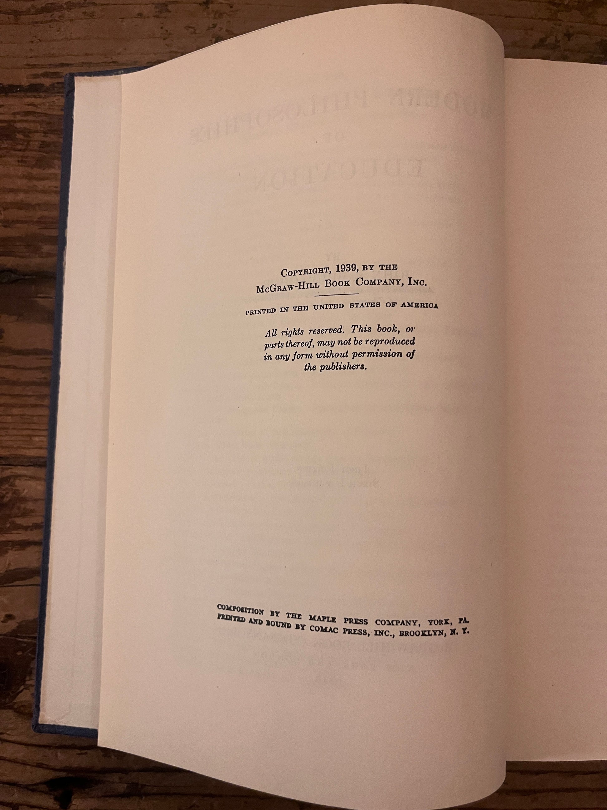 photo of the half title page of the book "modern philosophies of educatio" on a wooden background