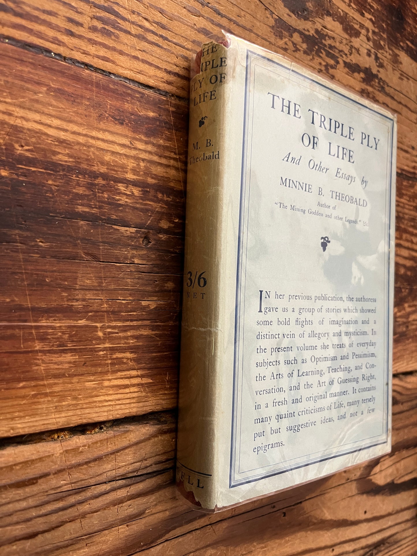 Spine book titled 'The Triple Ply of Life' by Minnie E. Theobald on a wooden surface