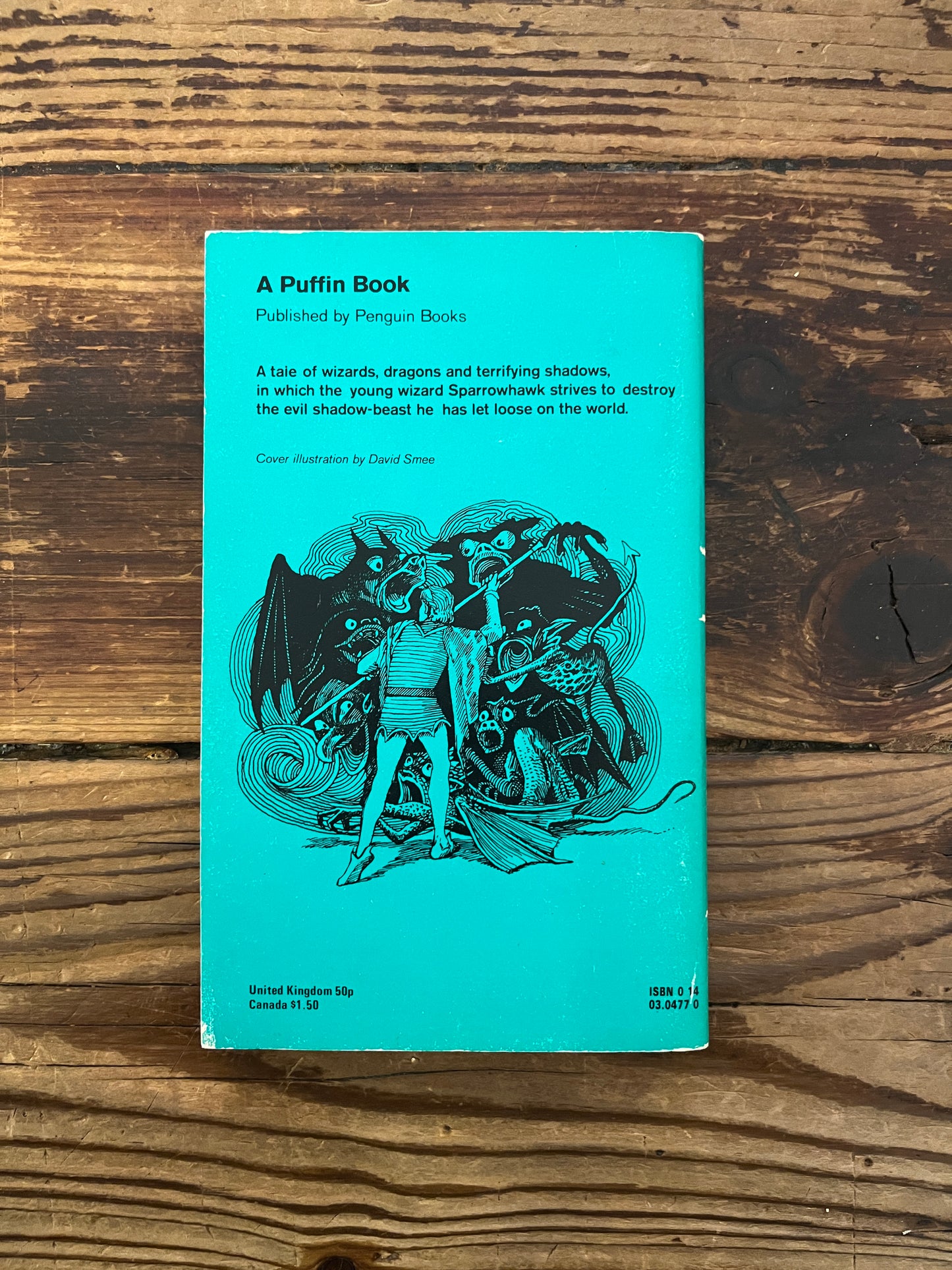 Back cover of book 'a Wizard of Earthsea' by Ursula K. Le Guin on a wooden surface 