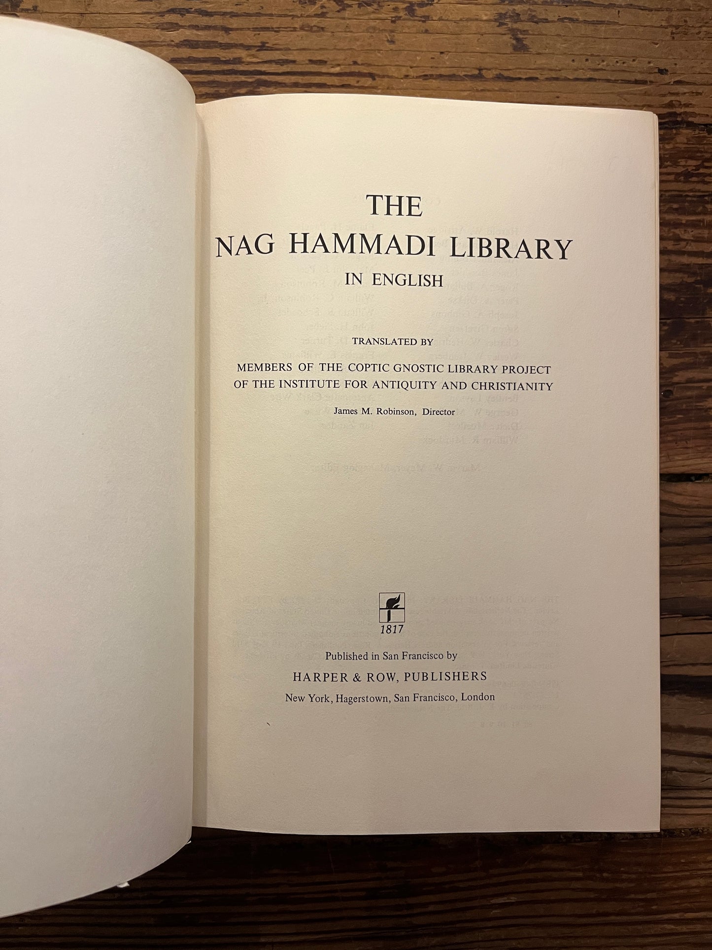 Open book titled 'The Nag Hammadi Library in English' on a wooden surface