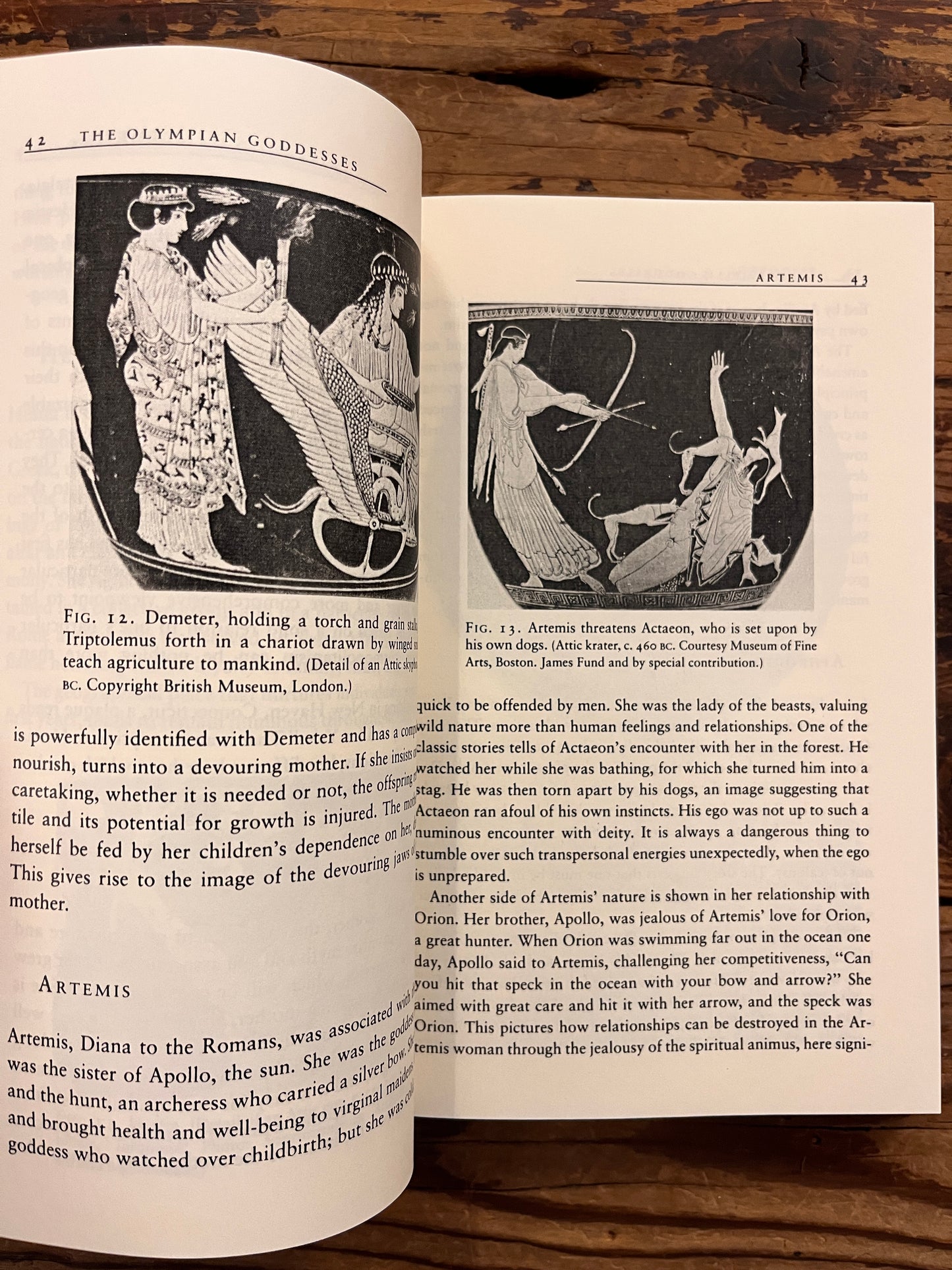 Open book titled 'The Eternal Drama: Greek Mythology' by Edward T. Edinger lying on a wooden surface