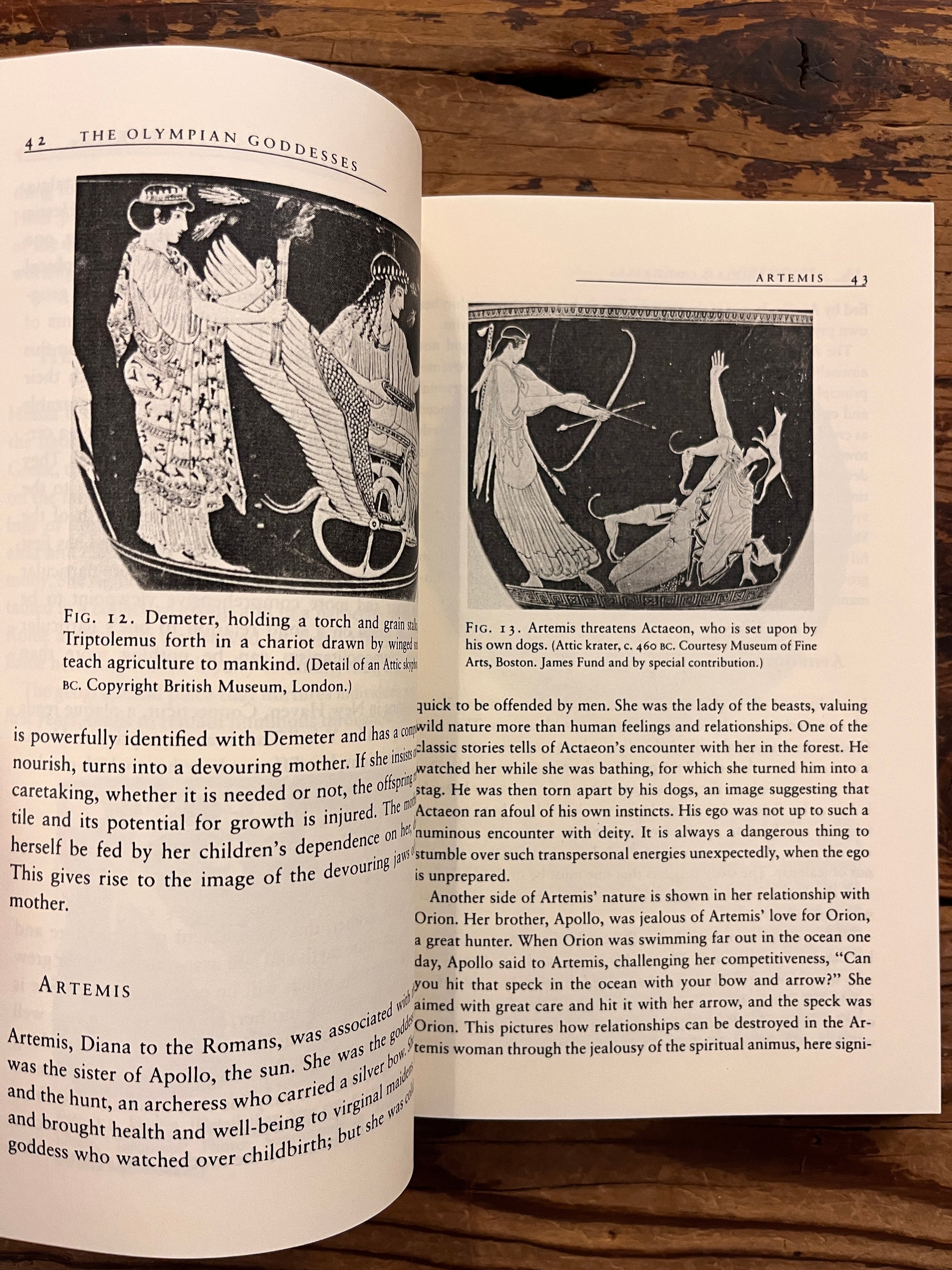 Open book titled 'The Eternal Drama: Greek Mythology' by Edward T. Edinger lying on a wooden surface