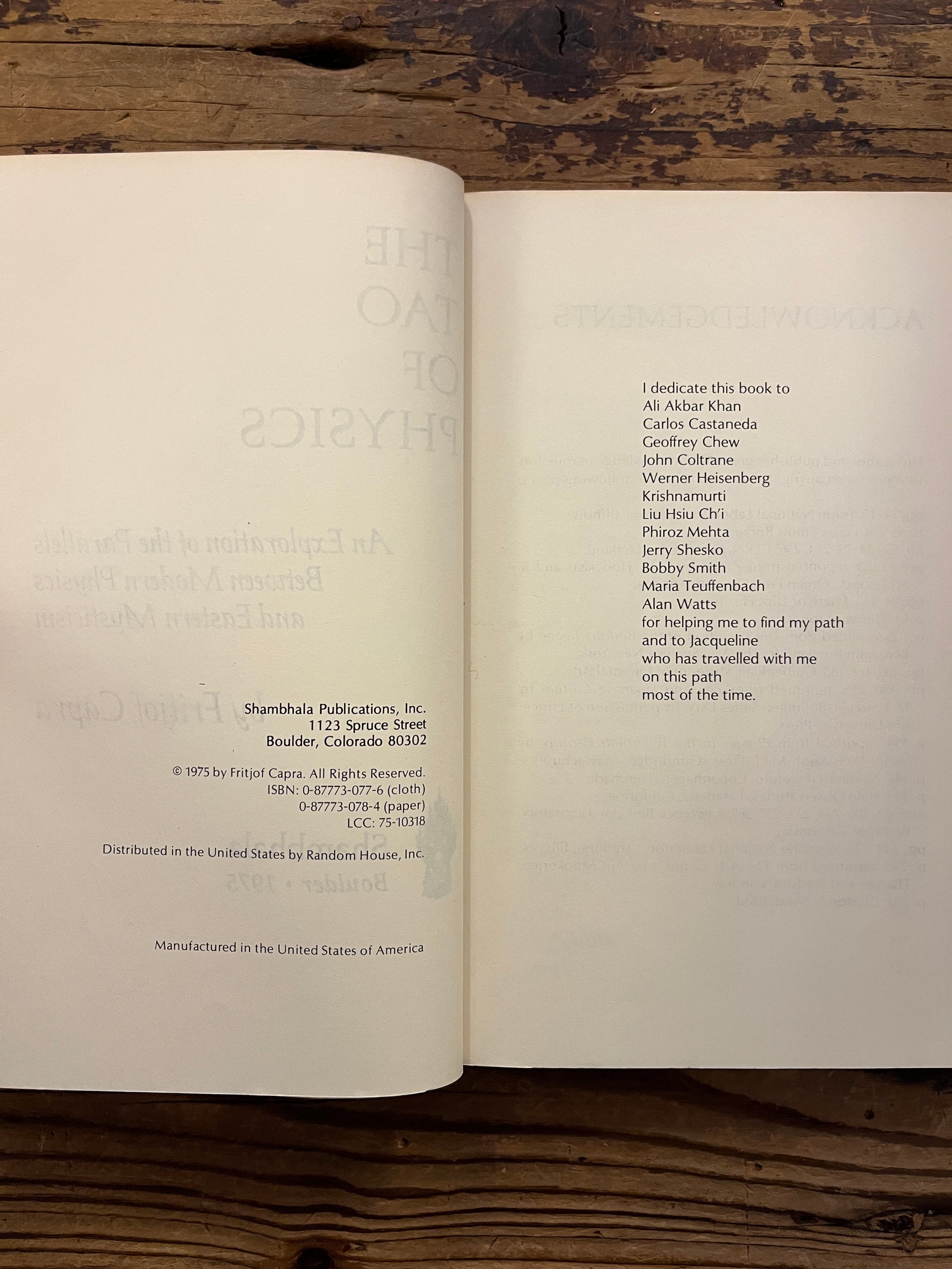 Open book titled 'The Tao of Physics' by Fritjof Capra on a wooden surface