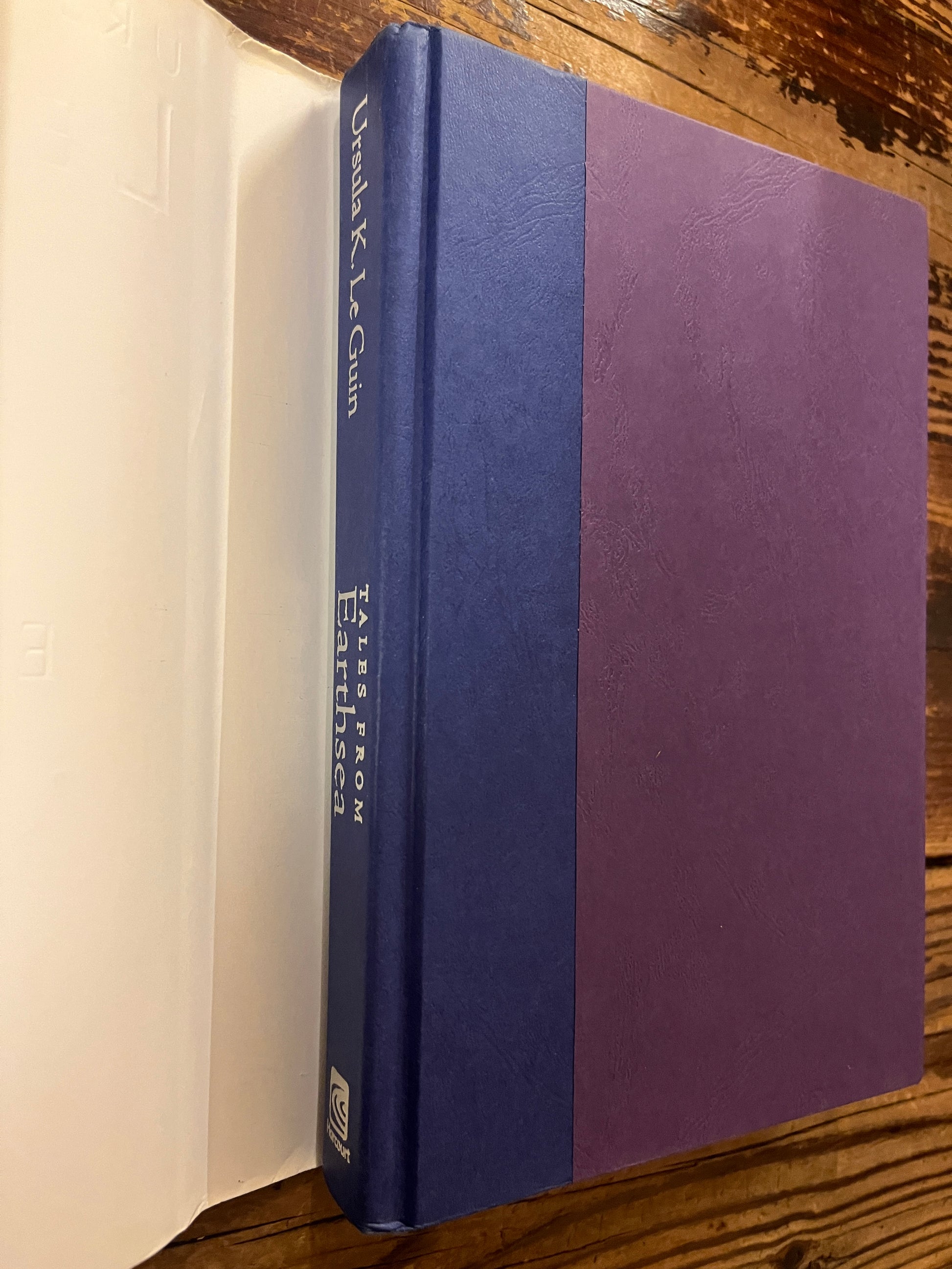 Book under dust jacket  titled 'Tales from Earthsea' by Ursula K. Le Guin on a wooden surface