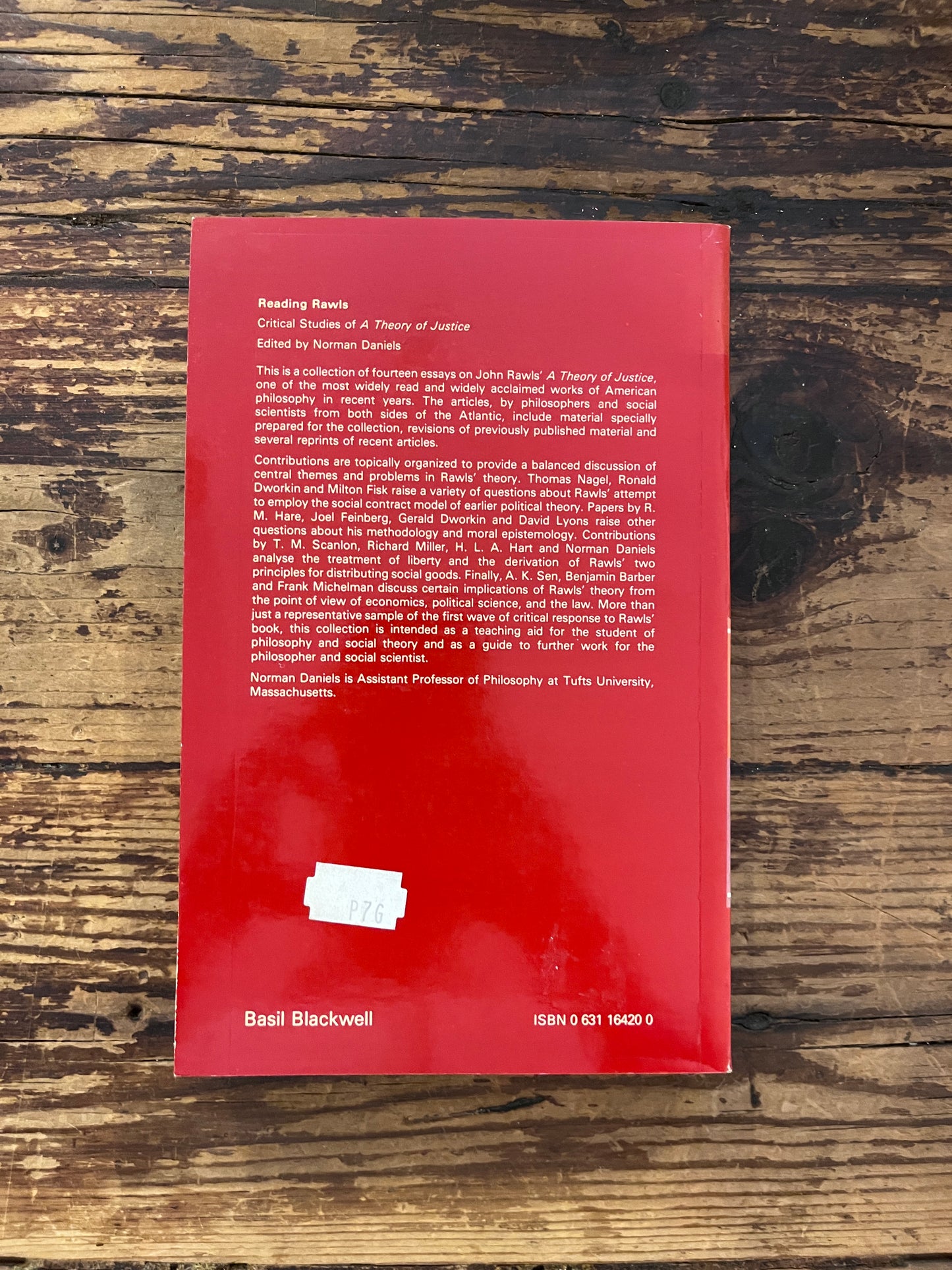 photo of the backcover of the book "Critical studies of a theory of justice"on a wooden background