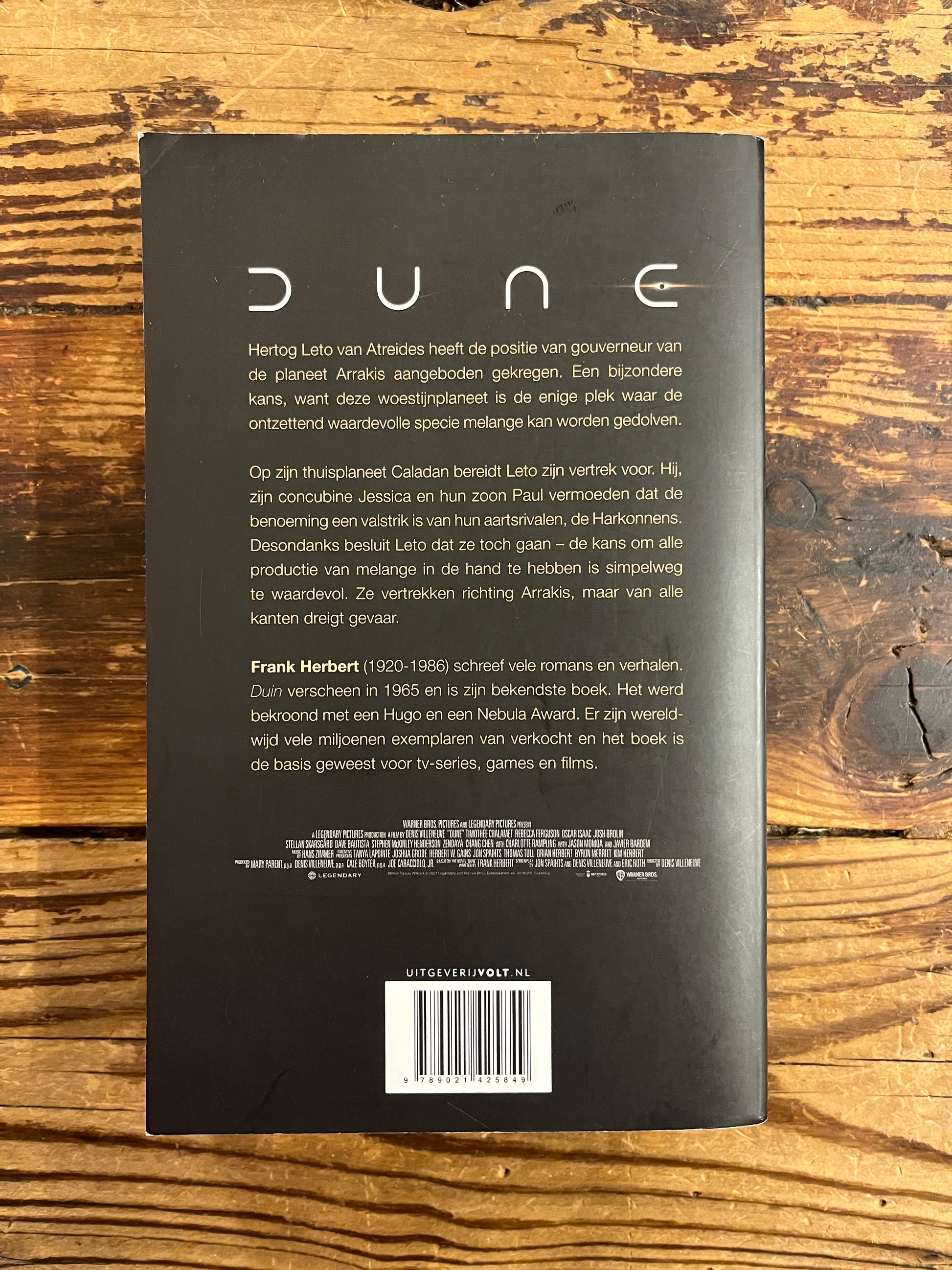 Achterkant van boek met de titel 'Dune' door Frank Herbert op een houten achtergrond