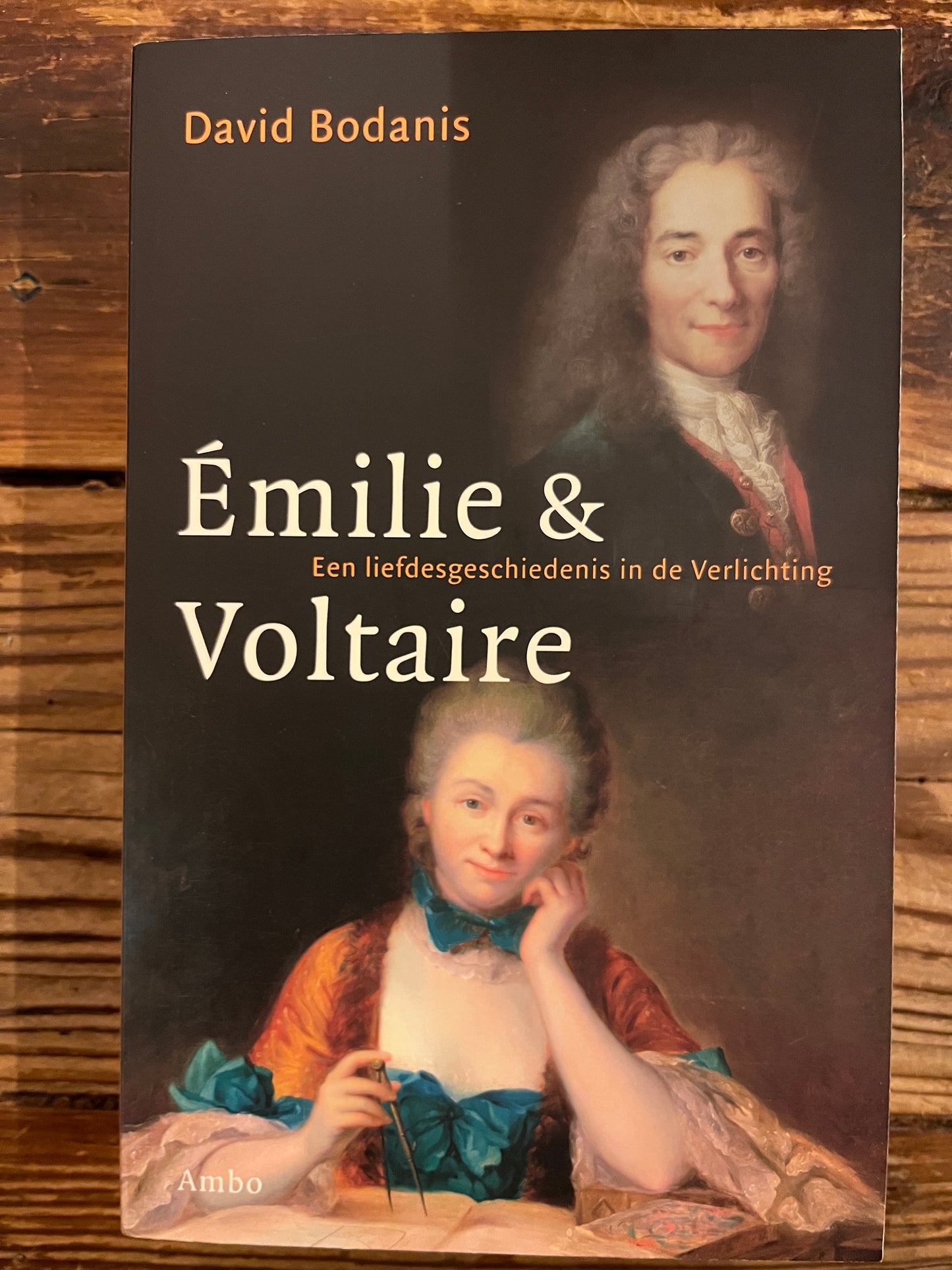 Voorkant van boek met de titel 'Emilie & Voltaire' door David Bodanis op een houten achtergrond 