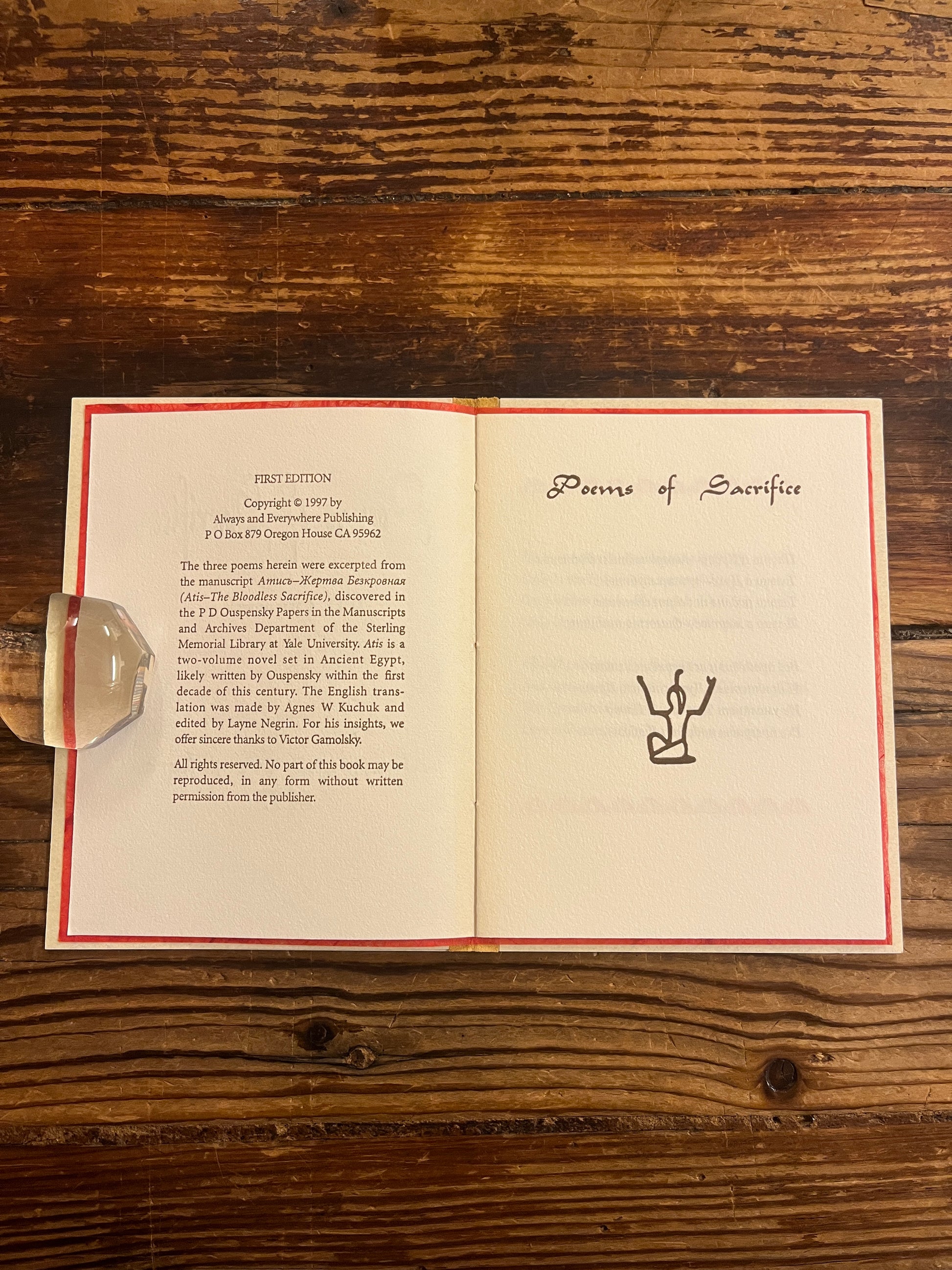 Open book titled 'Poems of Sacrifice' by P.D. Ouspensky on a wooden surface
