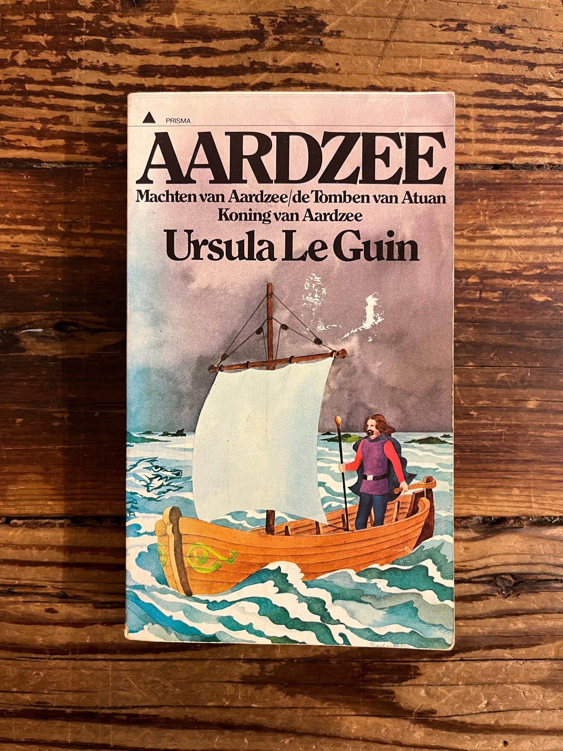 Voorkant van boek met de titel 'Aardzee' door Ursula K Le Guin op een houten achtergrond 