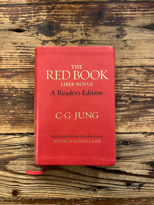 Red book titled 'The Red Book' by C.G. Jung on a wooden surface