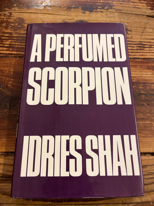Book titled 'A Perfumed Scorpion' by Idries Shah on a wooden surface