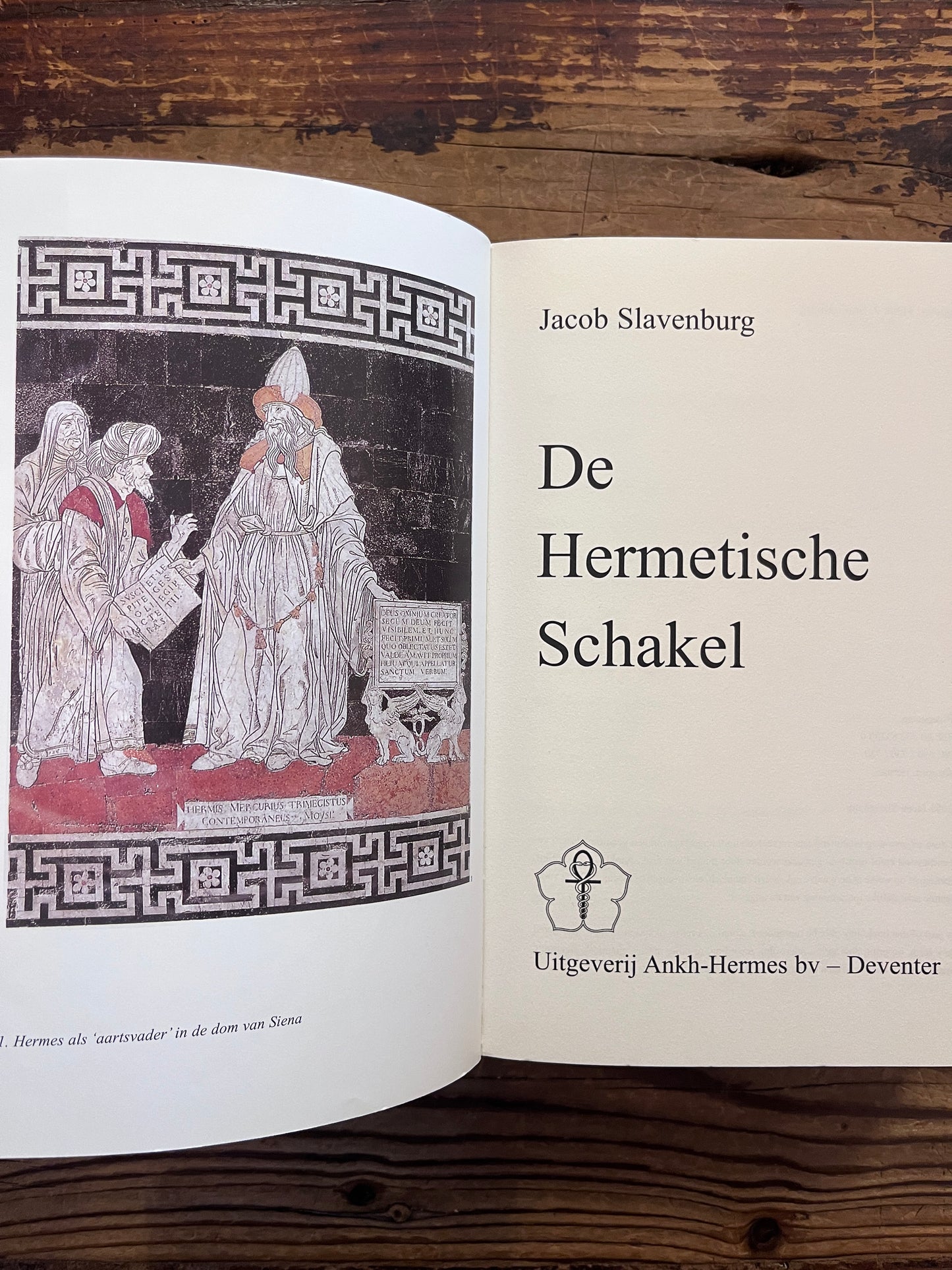 Open boek met de titel 'de Hermetische Schakel' door Jacob Slavenburg op een houten achtergrond 