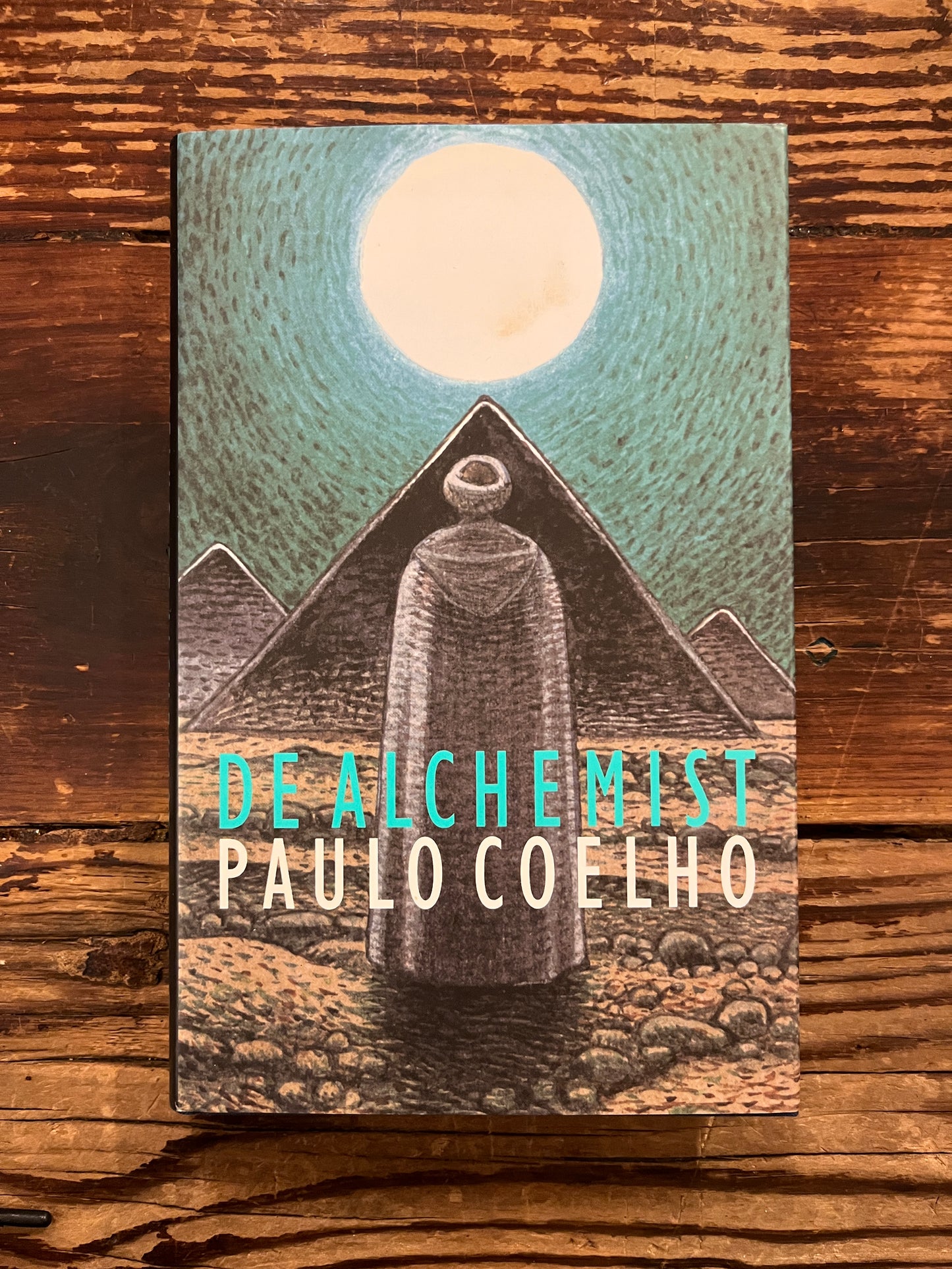 Boek 'De Alchemist' door Paulo Coelho op houten achtergrond 