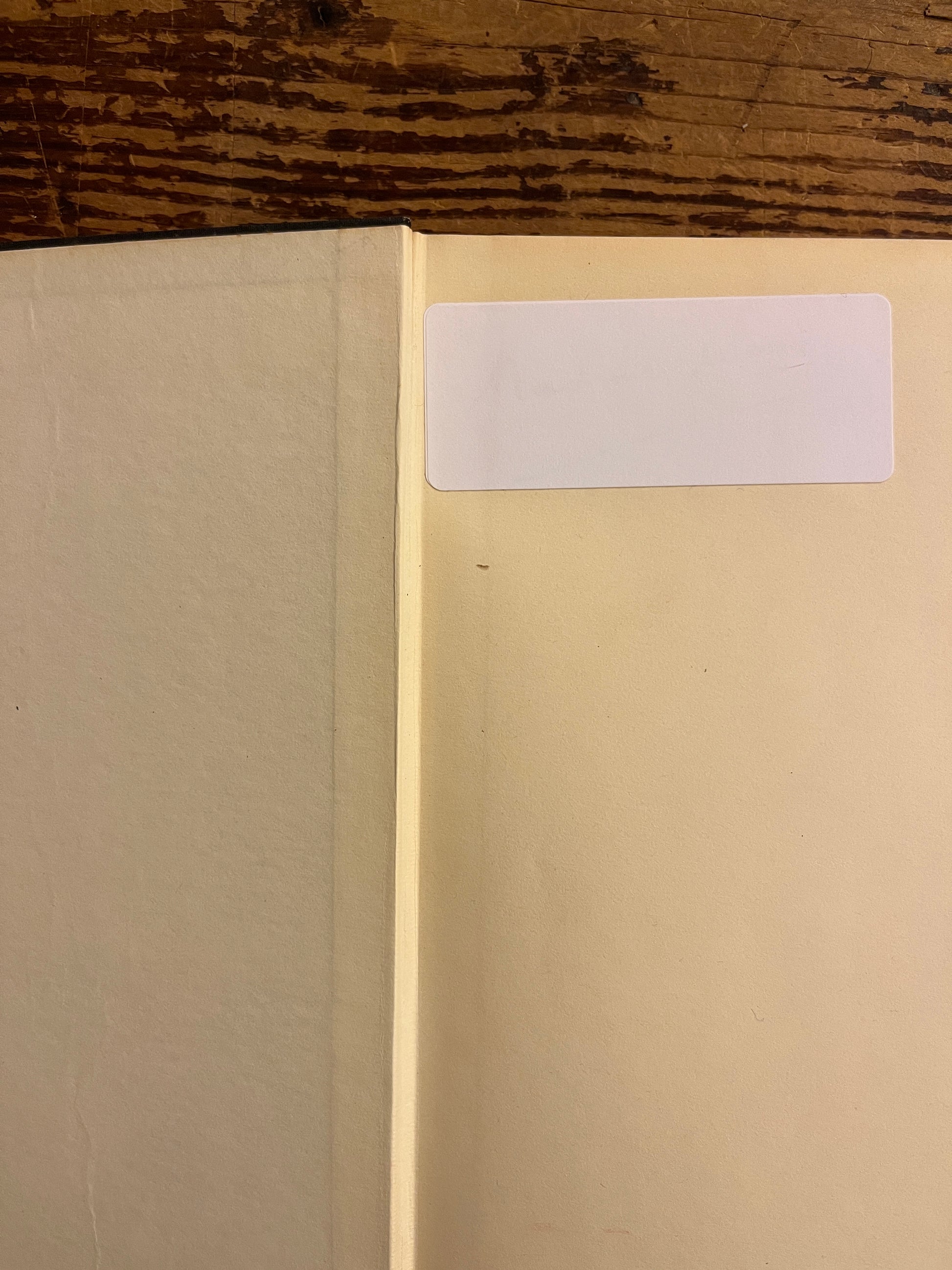 Open book showing a white sticker on the forst page of book titled 'Maurcie Nicoll a portrait' by Beryl Pogson on a wooden surface