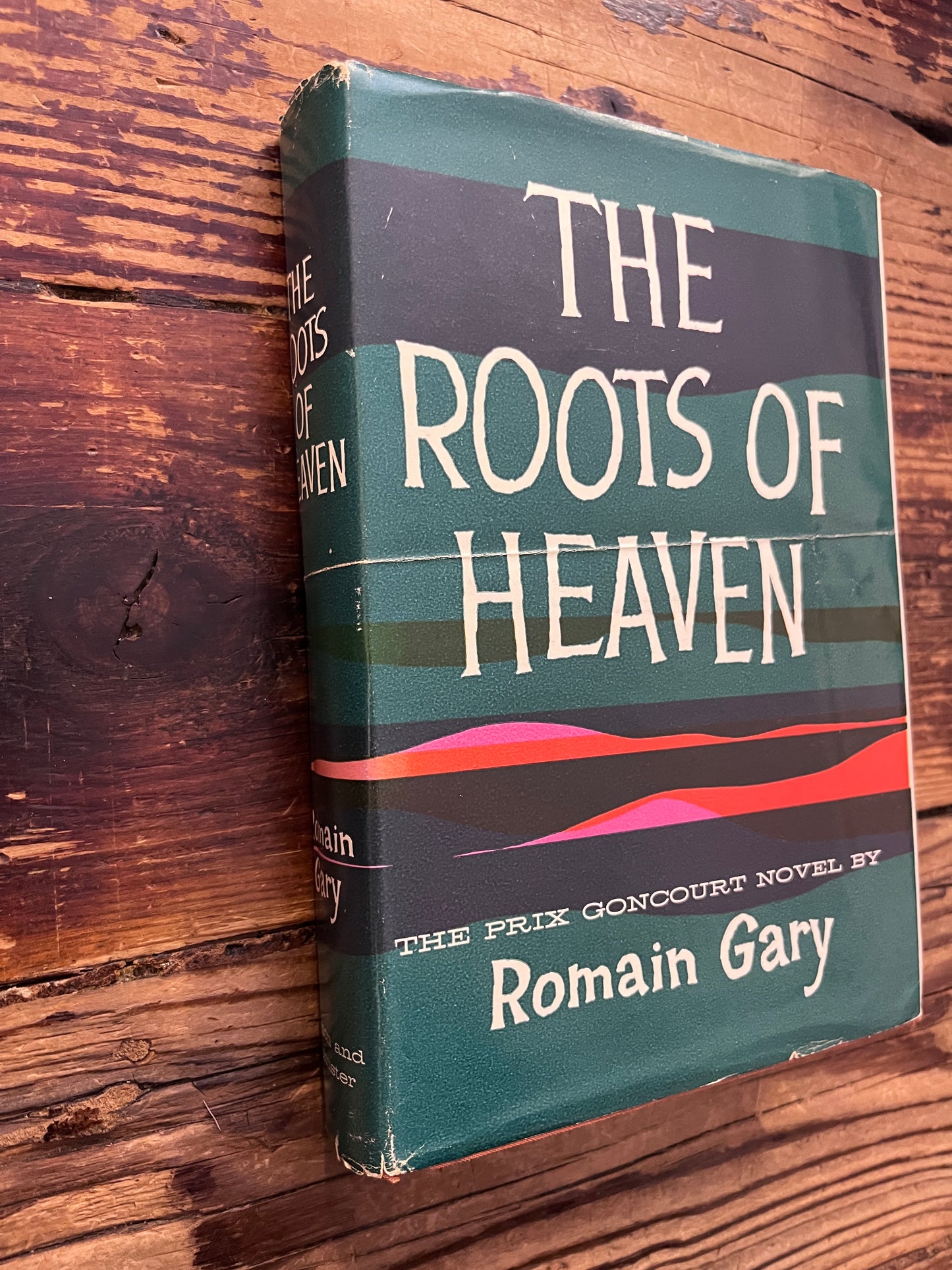 Book titled 'The Roots of Heaven' by Romain Gary on a wooden surface