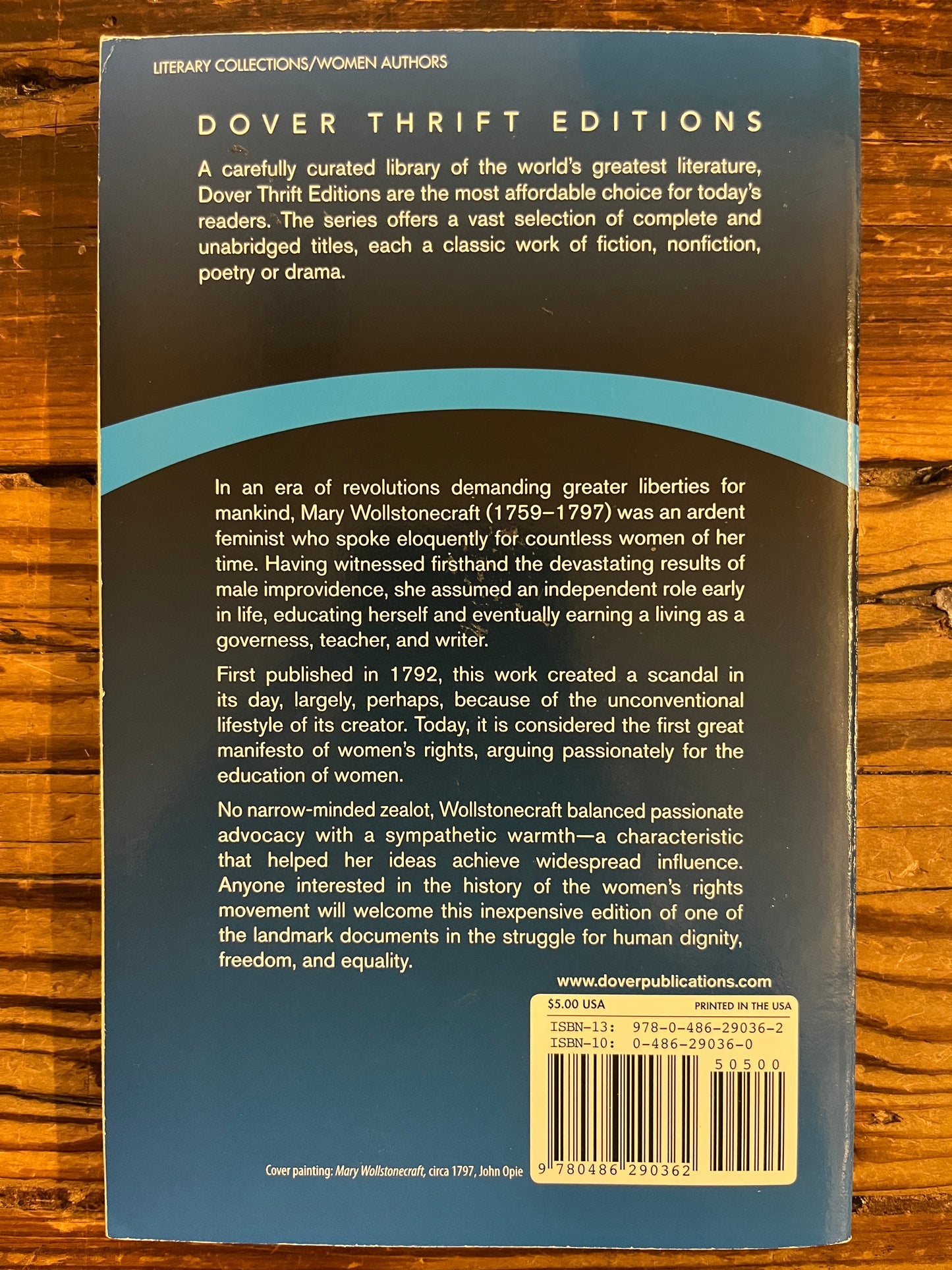 Back cover of book titled 'A Vindication of the Rights of Woman' by Mary Wollstonecraft on a wooden surface