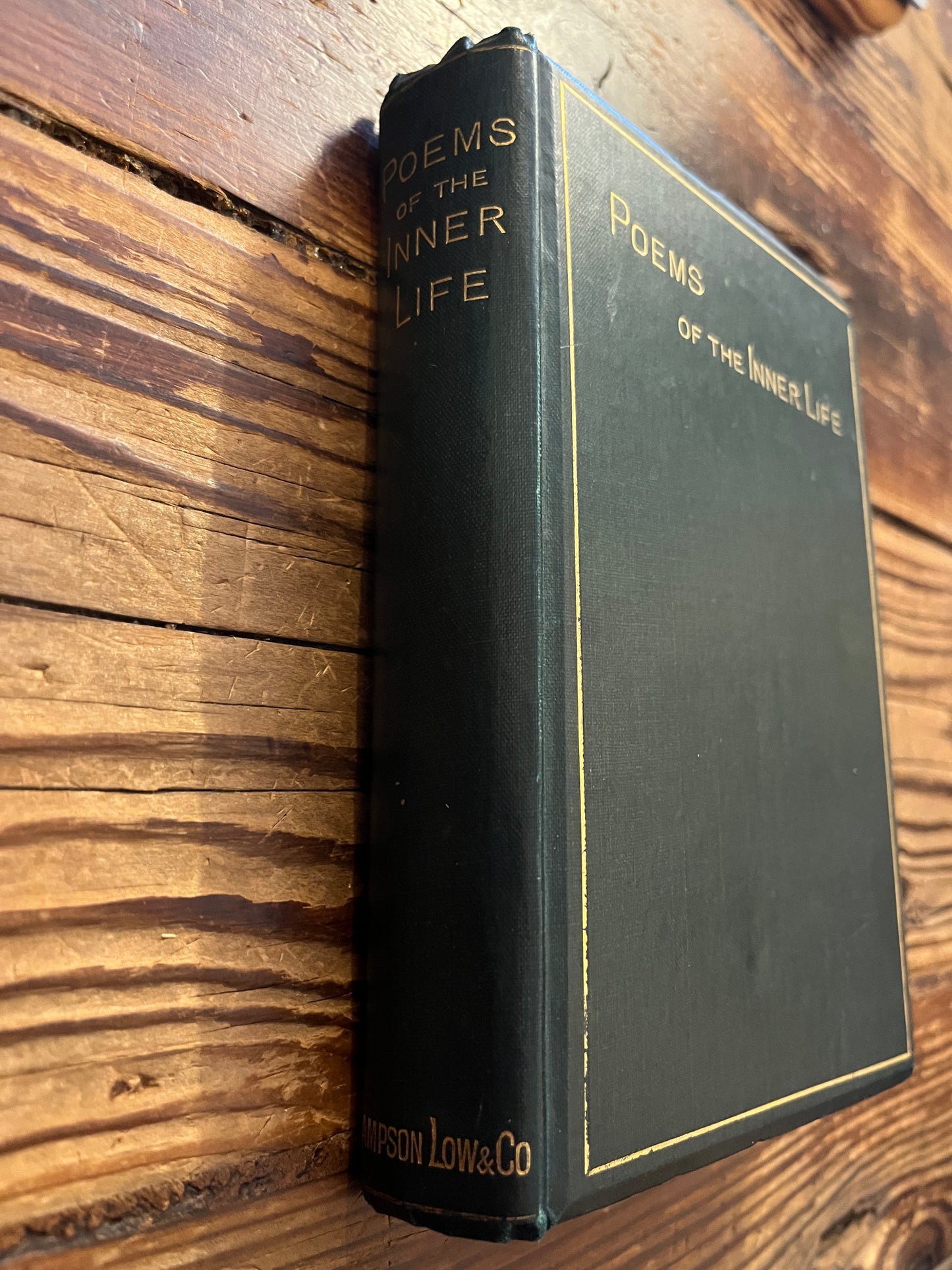 Spine of book titled 'Poems of the Inner Life' on a wooden surface